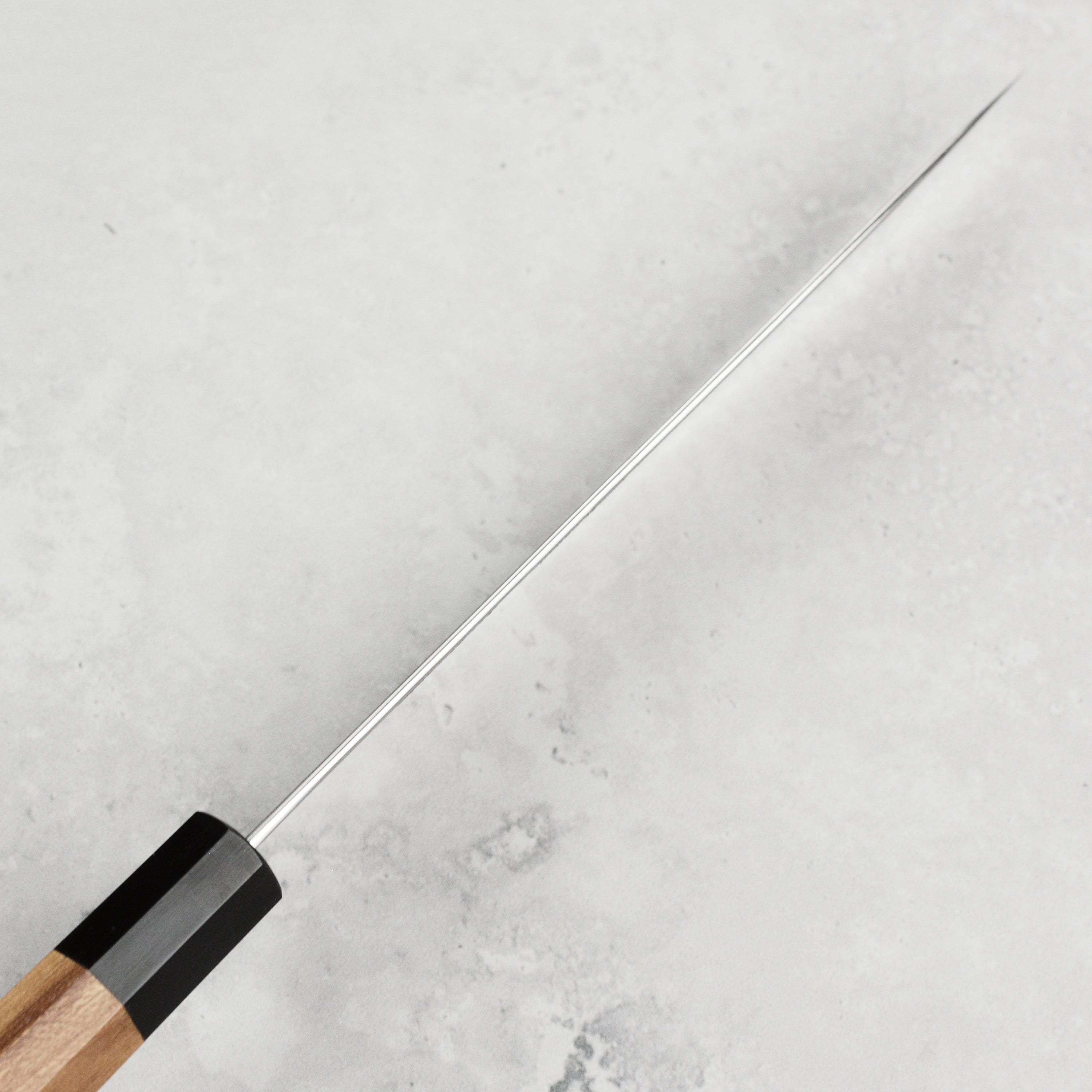 Teak wood handle of the Enso carbon steel petty knife highlighting its craftsmanship.
