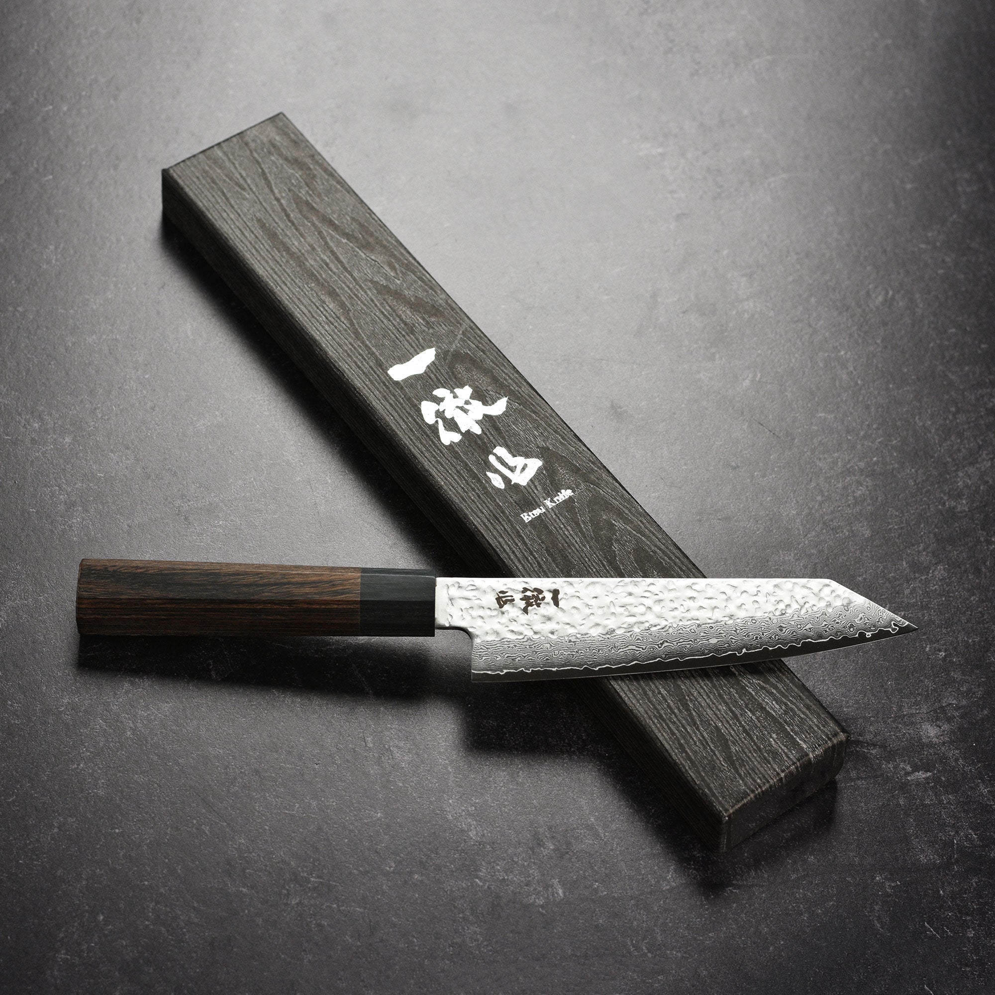 Full view of the Ittetsu VG10 Damascus Ko-Bunka knife on cutting board