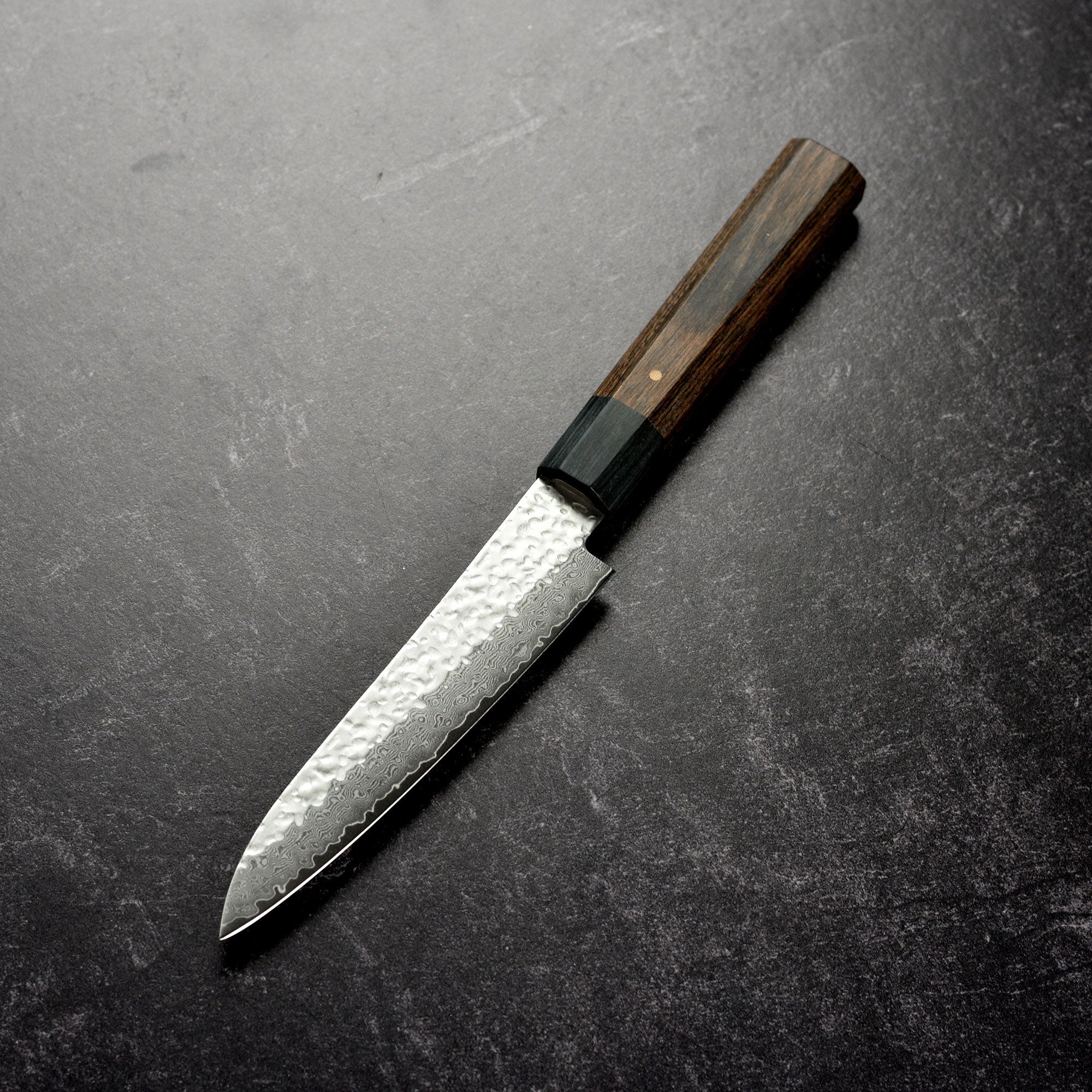 Ittetsu VG10 petty knife in action, slicing fresh vegetables on a wooden cutting board.