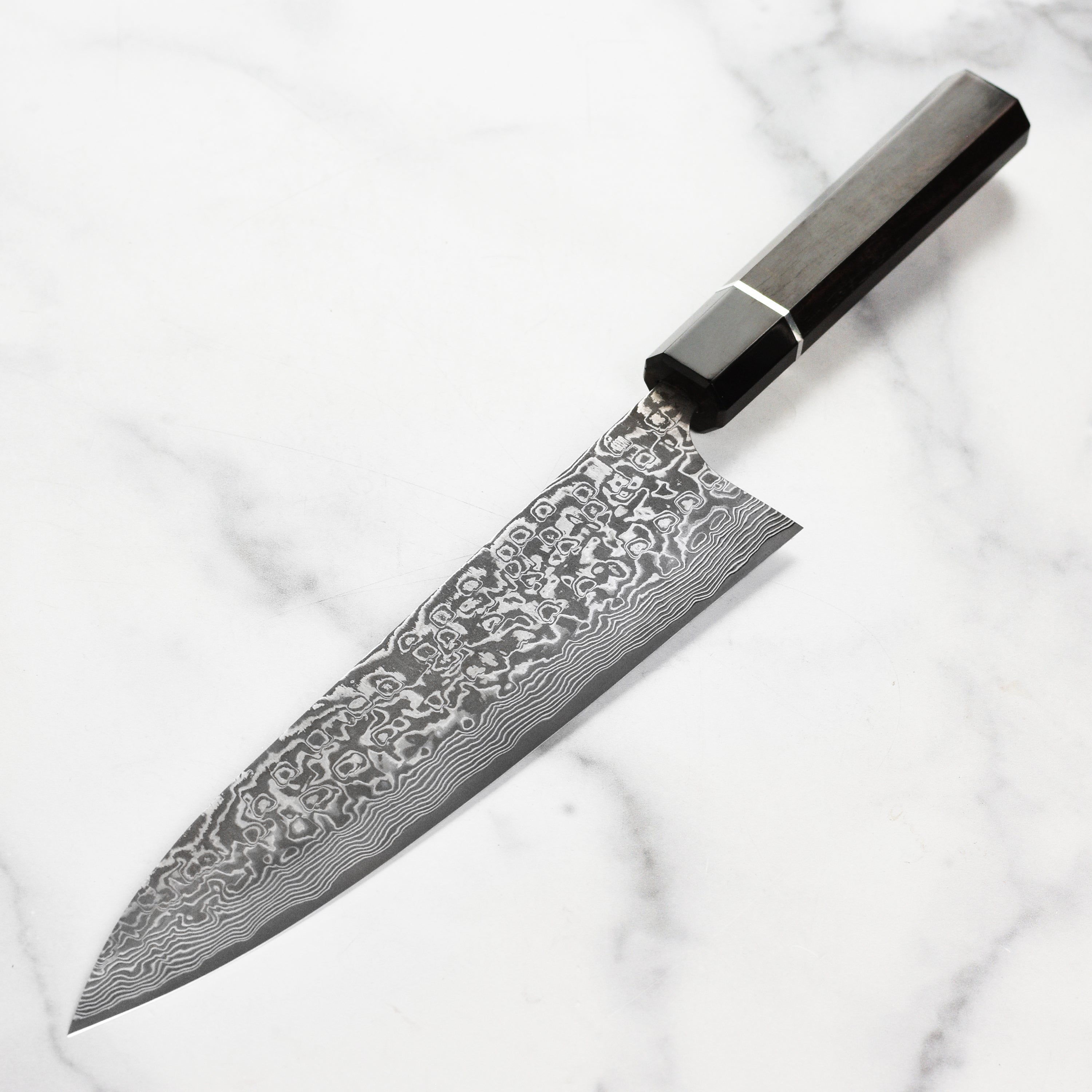 Close-up of the SG2 steel knife blade revealing intricate Damascus patterns and the sharp edge.