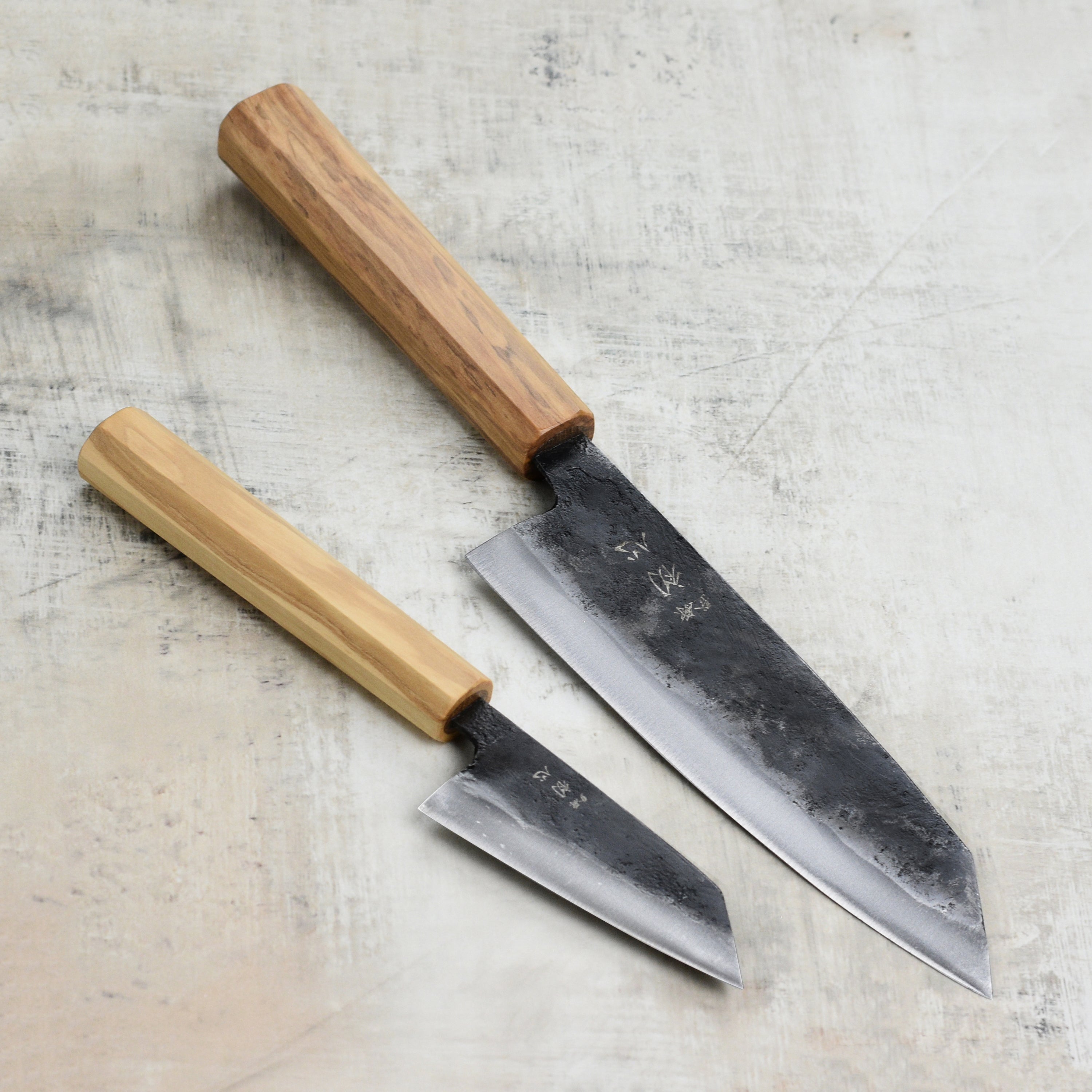 Hatsukokoro Aogami #2 Kurouchi Bunka Knife Set displayed on a wooden cutting board, showcasing its sleek design and high carbon steel blade.