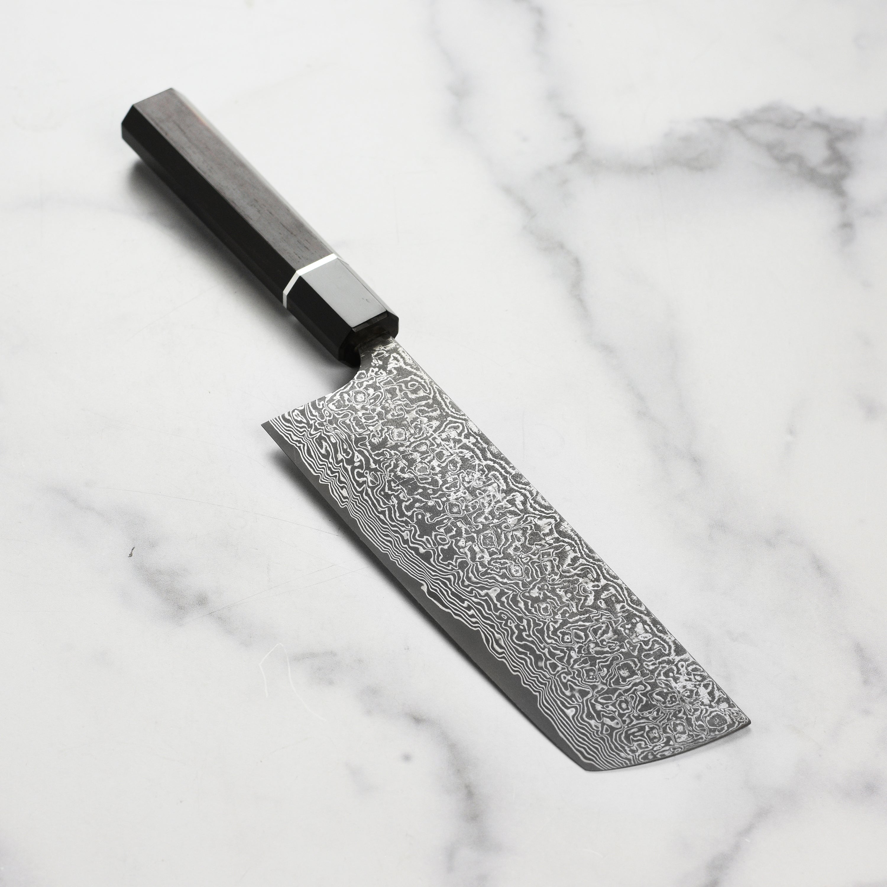 Close-up of the Saji SG2 Black Damascus Nakiri knife blade showcasing its intricate design.