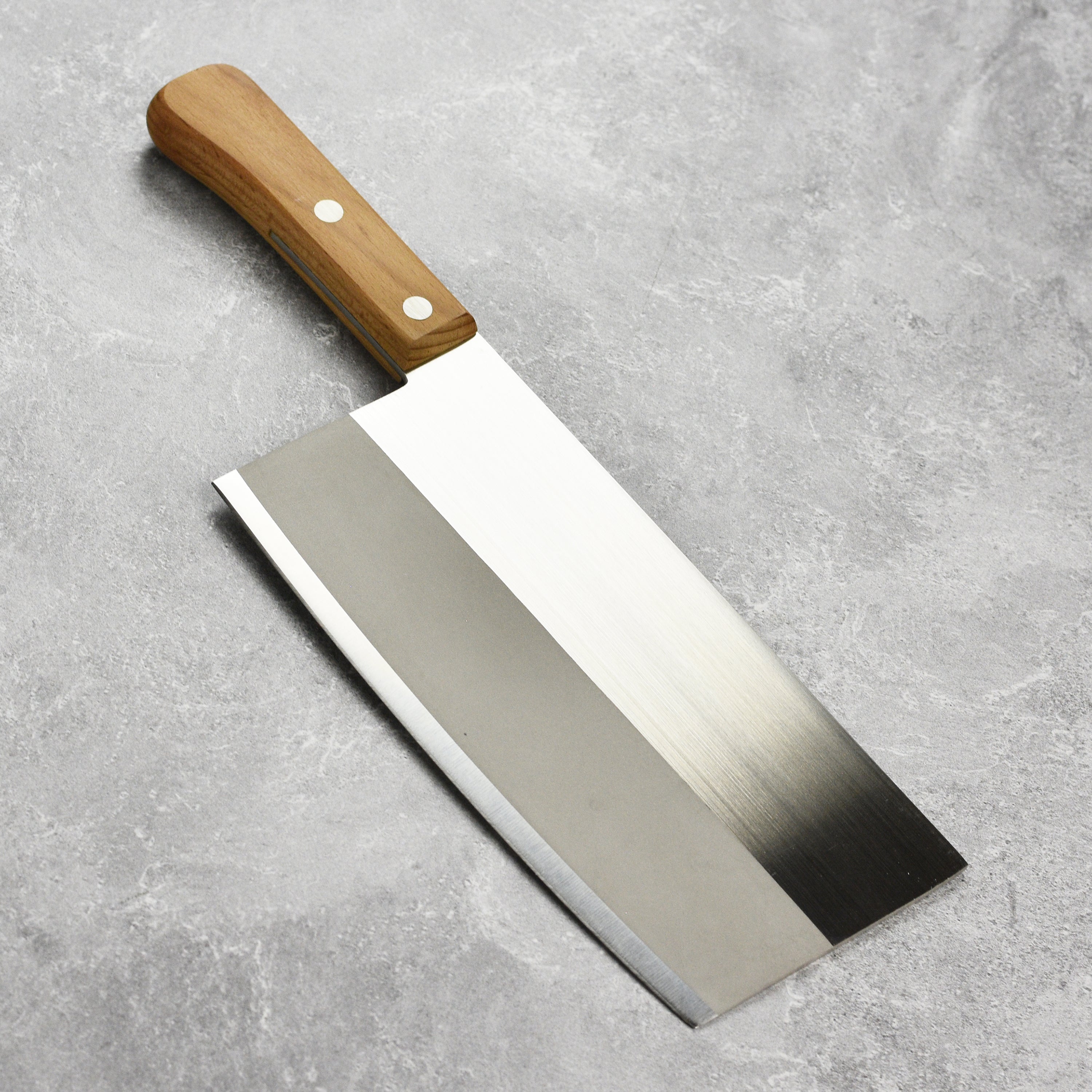 Home cook using a Chinese cleaver to prepare vegetables in a modern kitchen