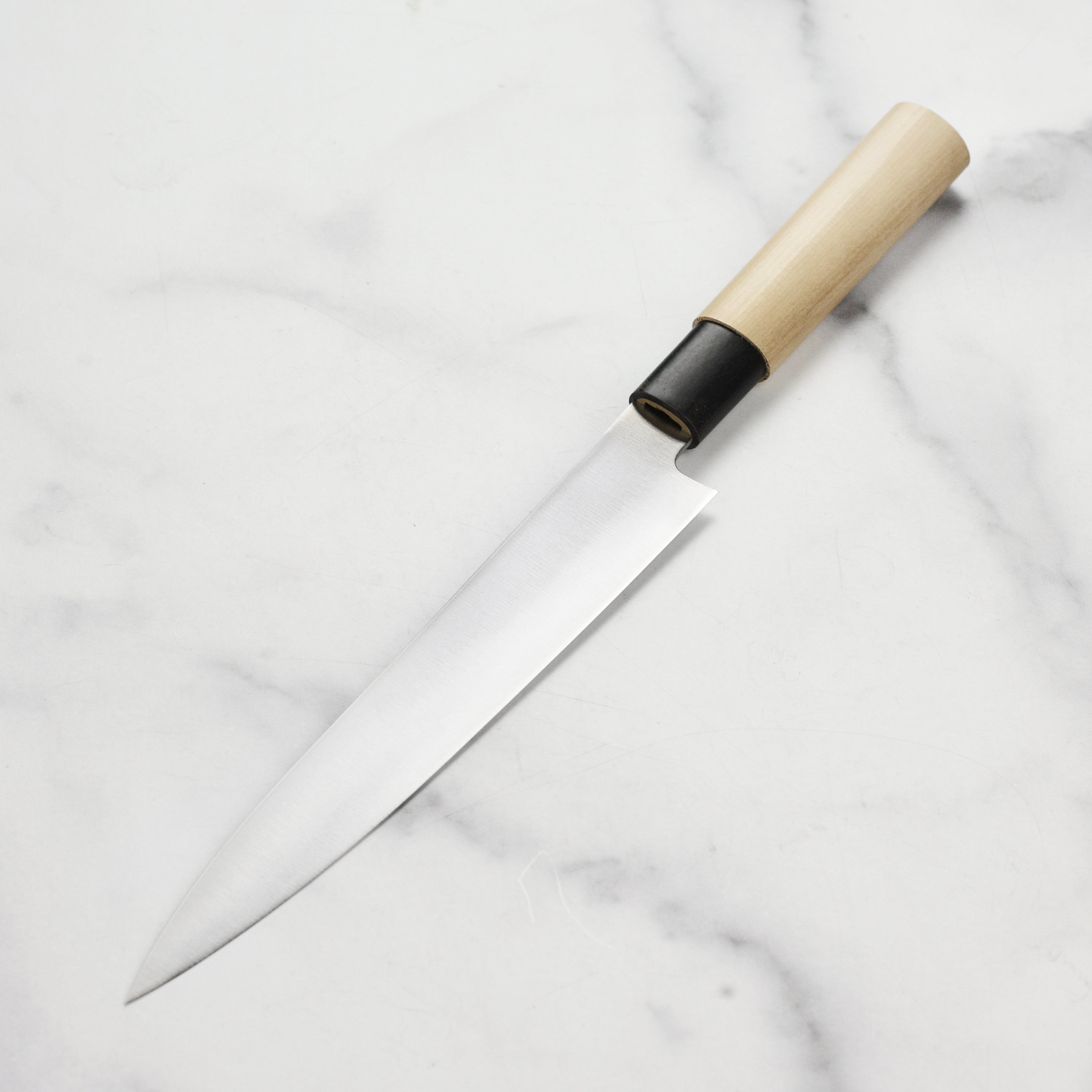 Close-up of the Tojiro MV yanagiba knife slicing fresh fish for sushi preparation.