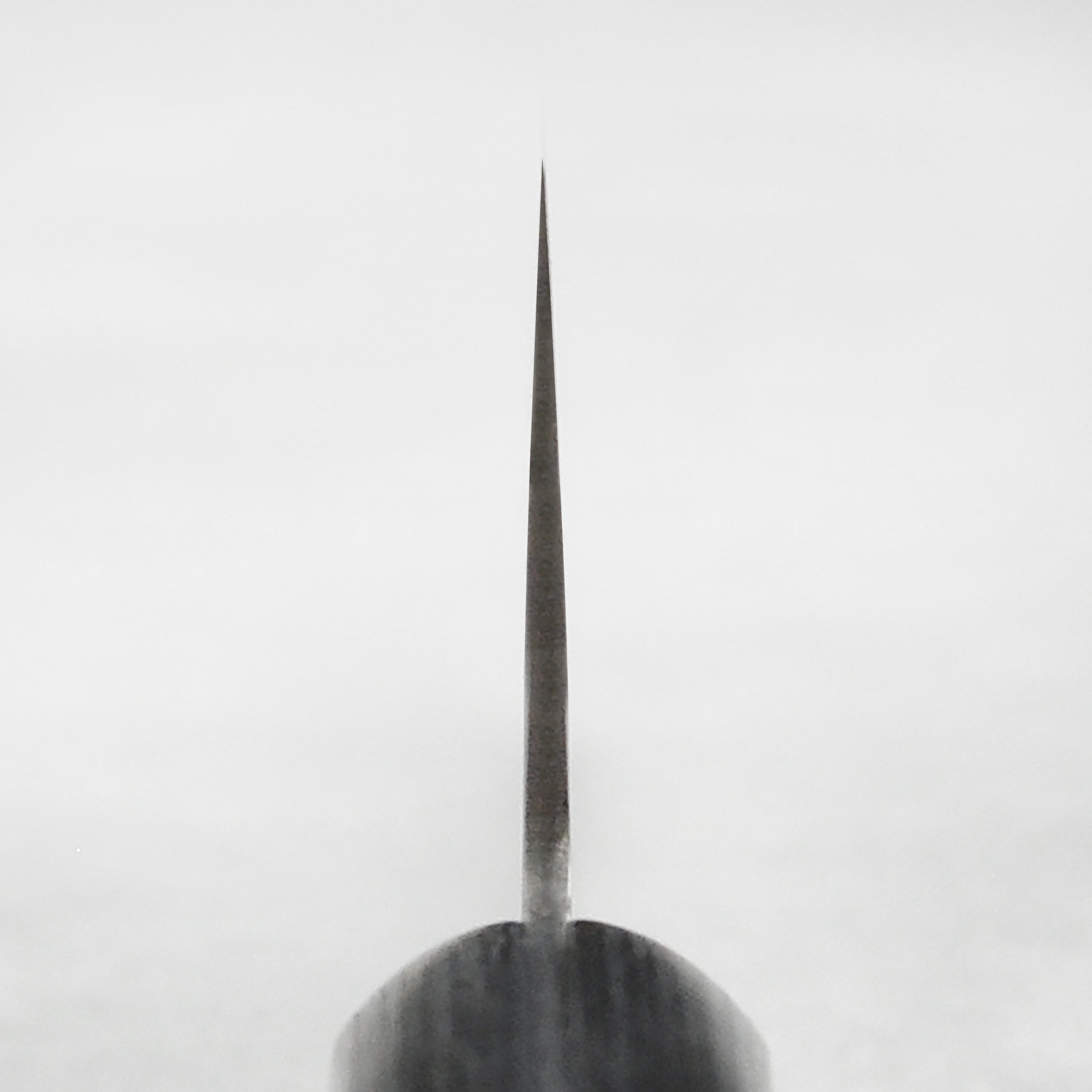 Tojiro VG-10 Santoku knife angled view on a wooden cutting board, highlighting its sharp blade and Pakkawood handle.