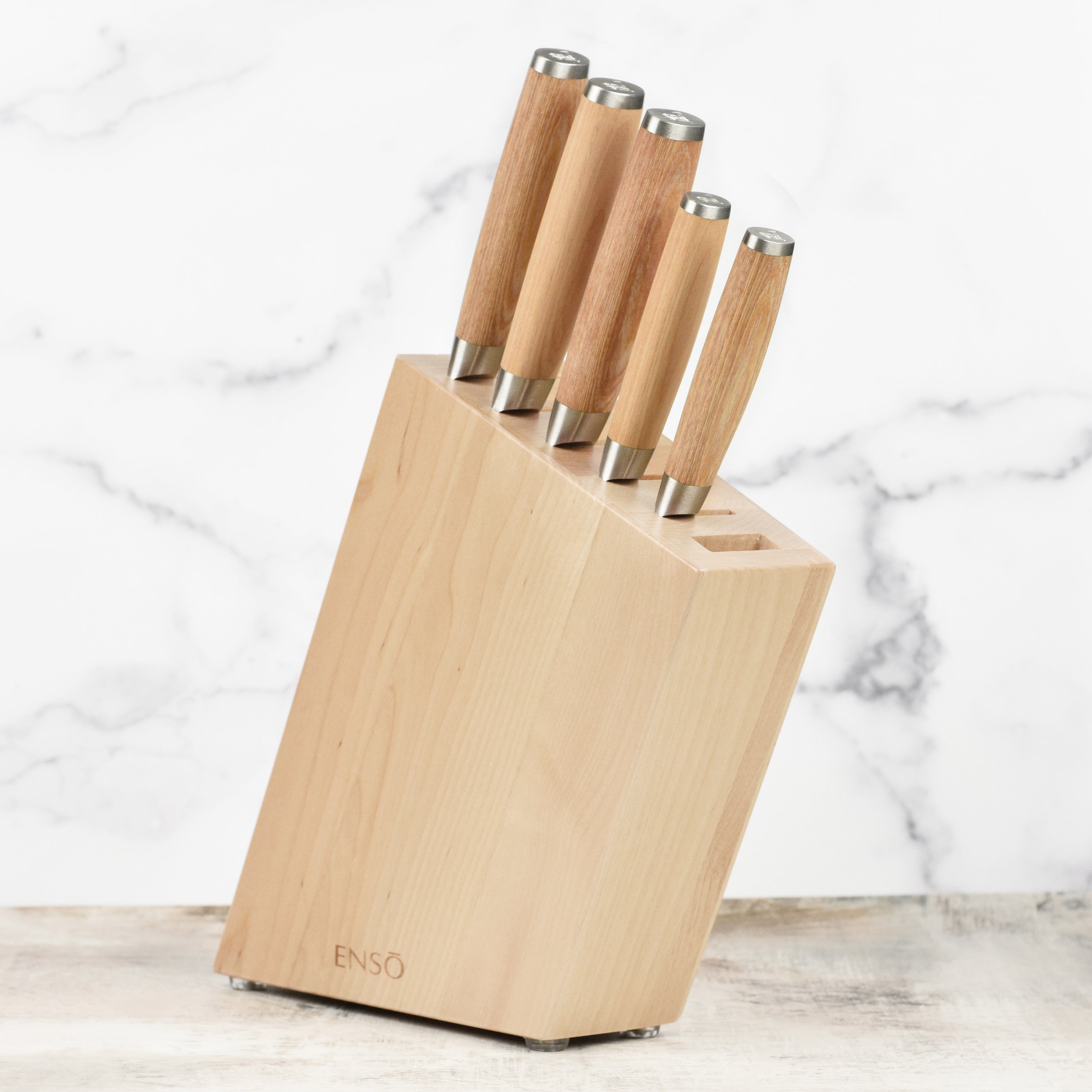 Side view of Enso Damascus chef knives displayed in a block, showing hammered finish and engraved end caps