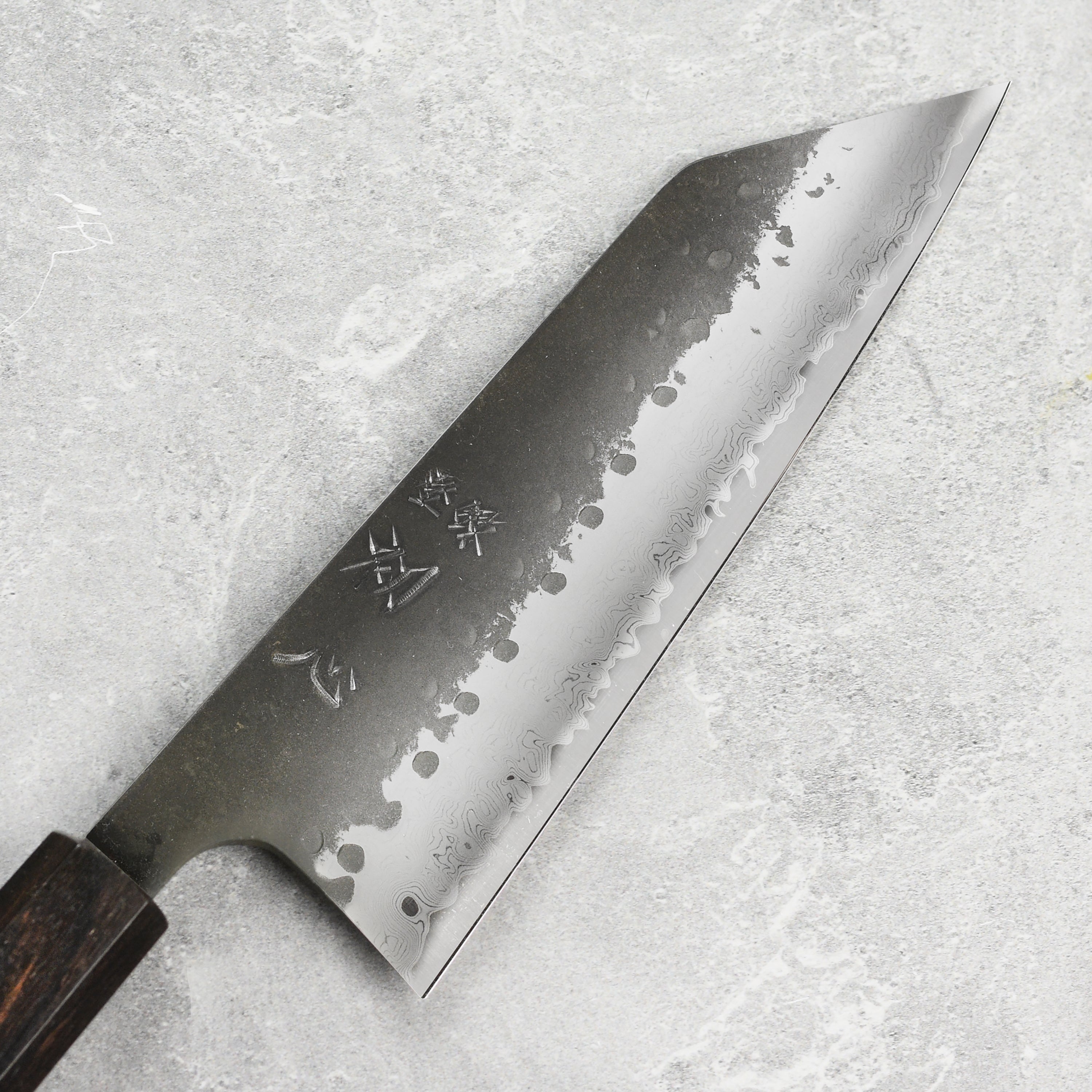 Hatsukokoro Aogami Super Bunka knife showing the blades detailed Damascus pattern from an angled view.