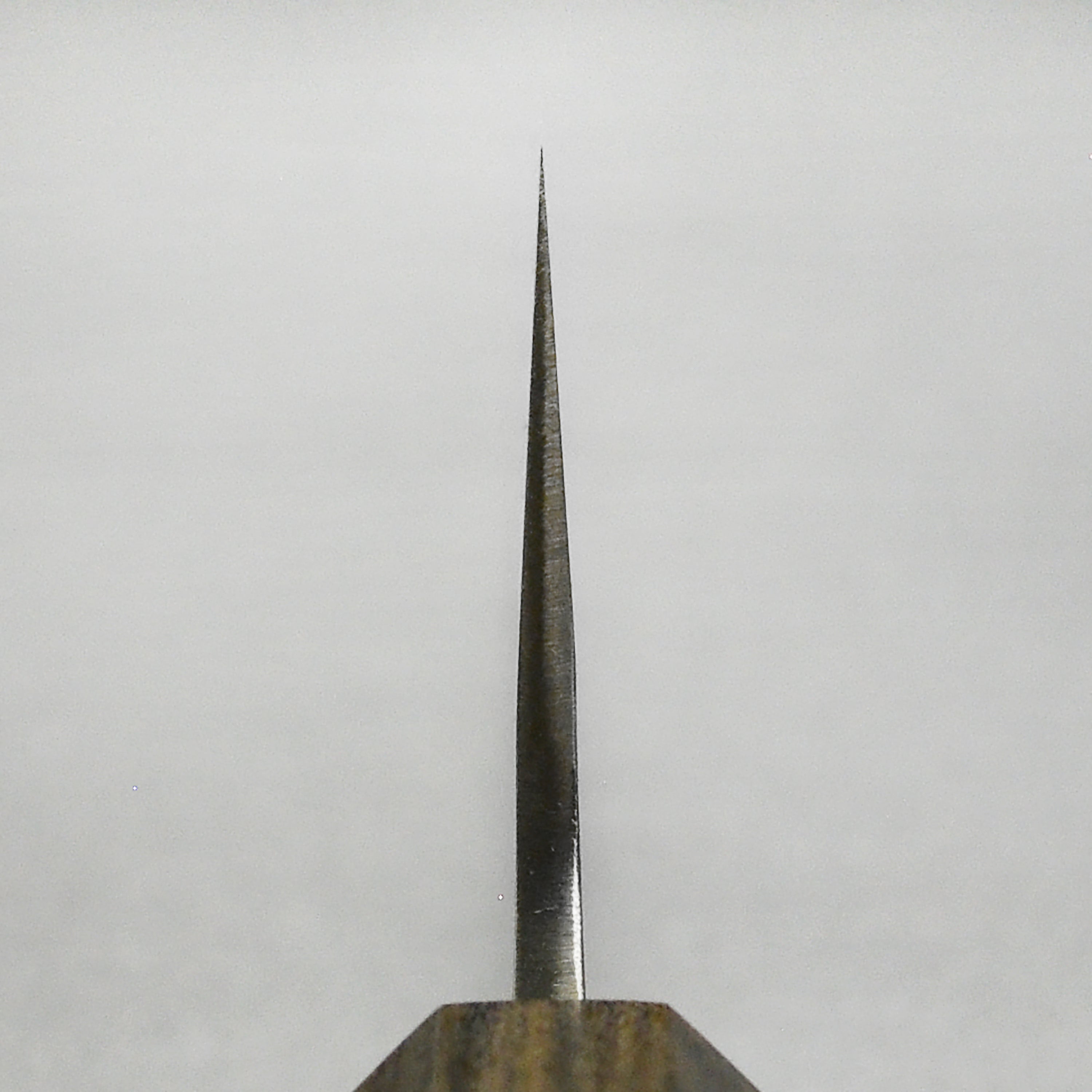 Yoshikane SKD Nashiji Gyuto Knife from a side angle, highlighting its sharp blade and sleek design.