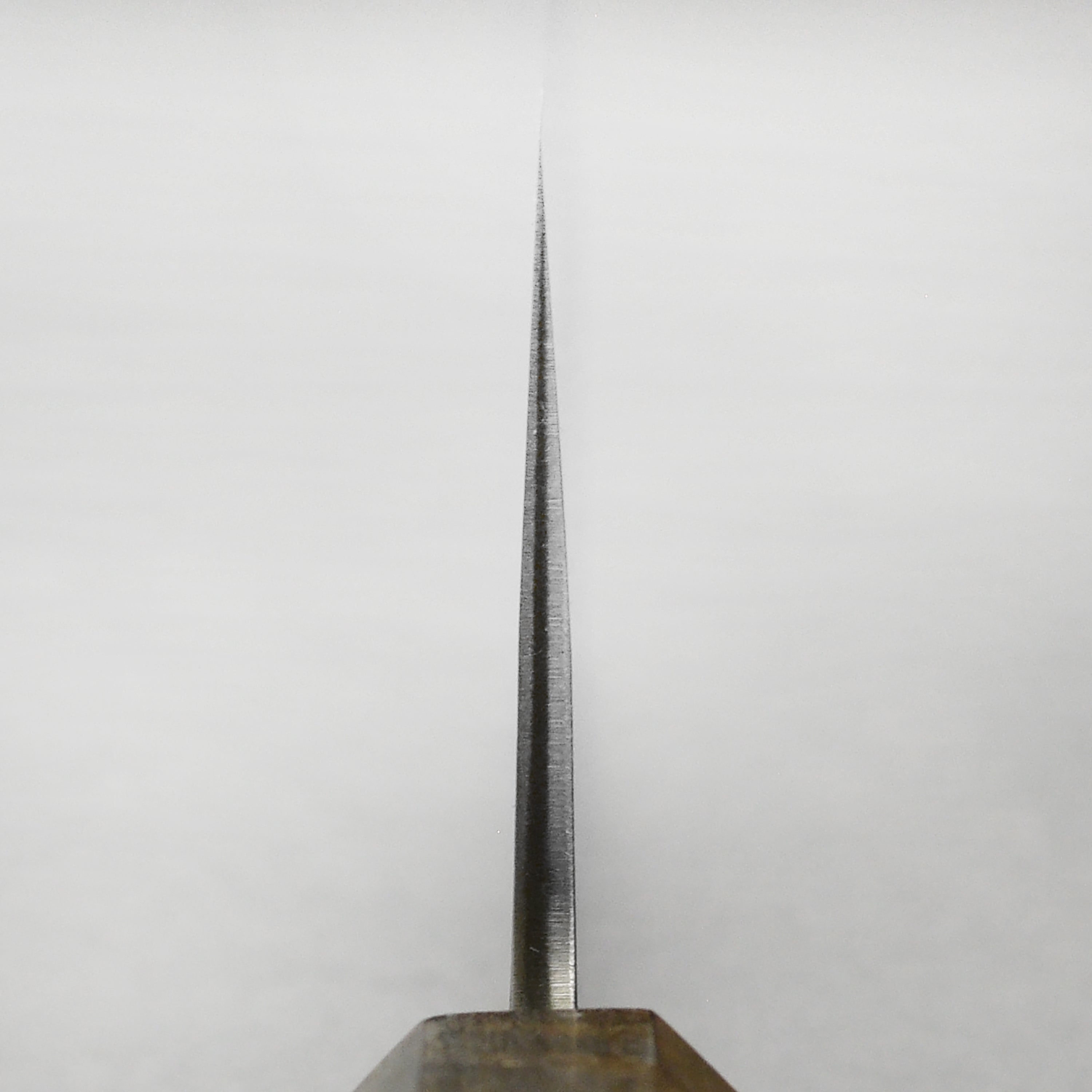 Yoshikane SKD Nashiji Nakiri knife from the side, highlighting its sharp edge and stainless steel finish.