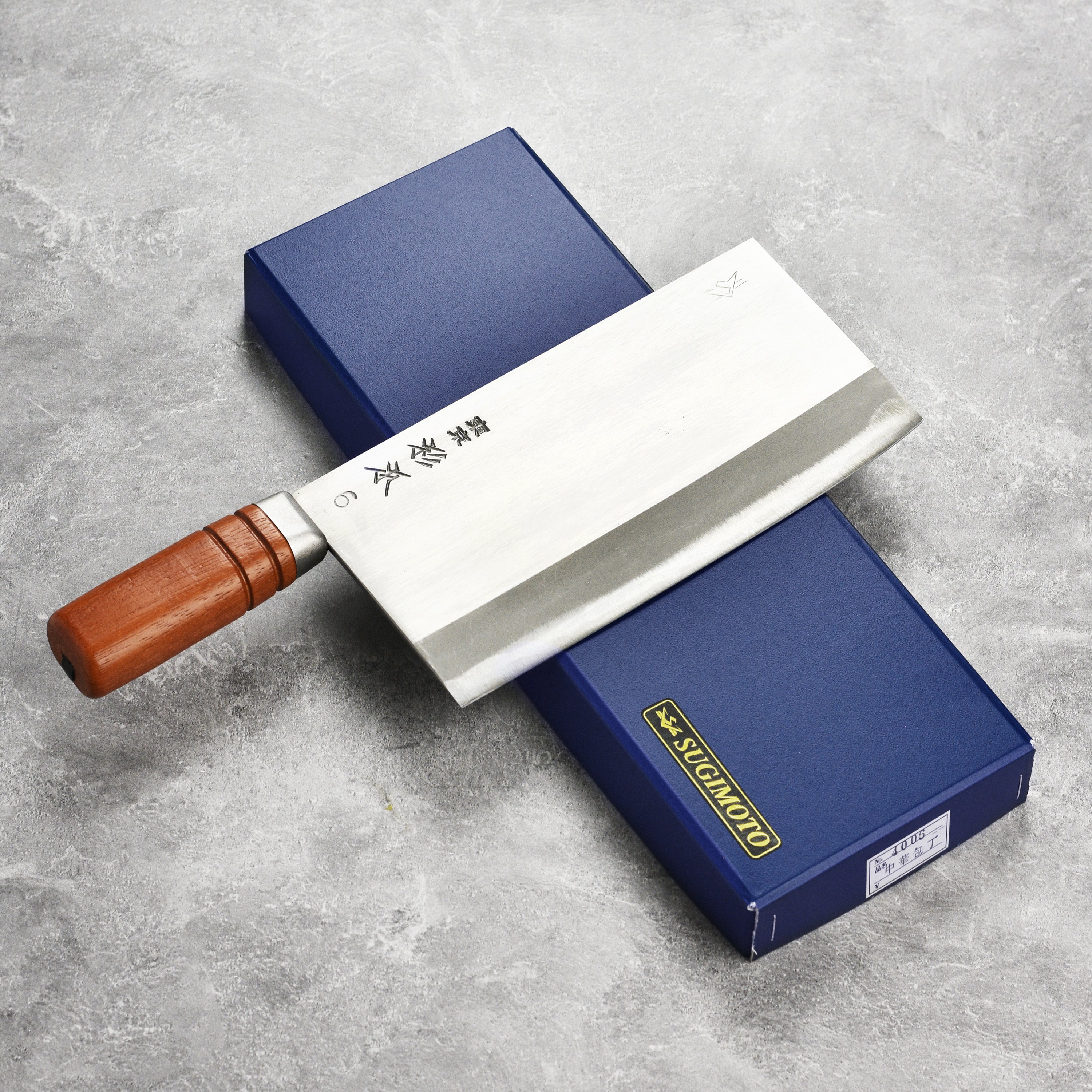Sugimoto cleaver in action, chopping vegetables on a wooden cutting board.