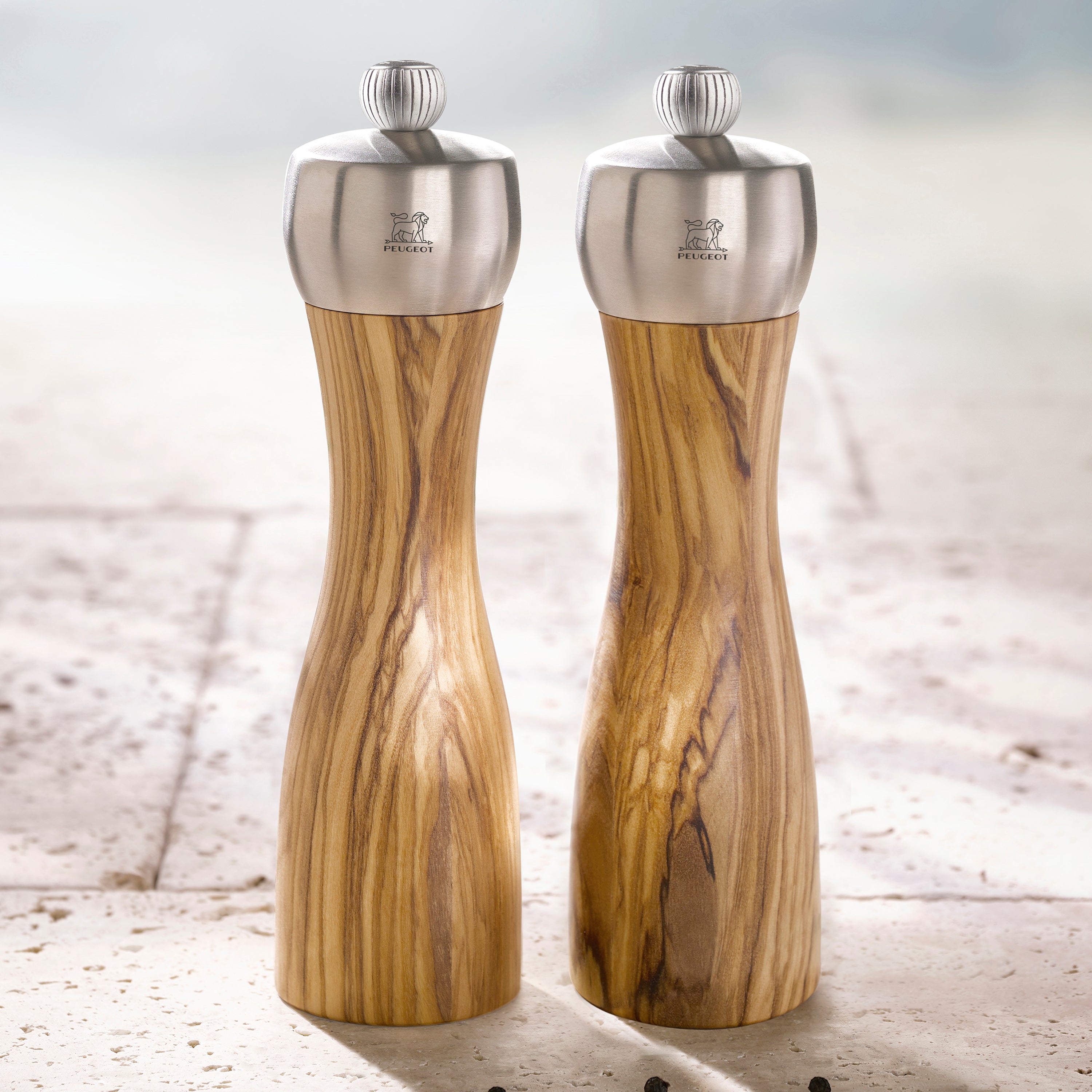 Close-up of Peugeot Fidji Olivewood Salt and Pepper Grinder Set showing the brushed stainless steel top