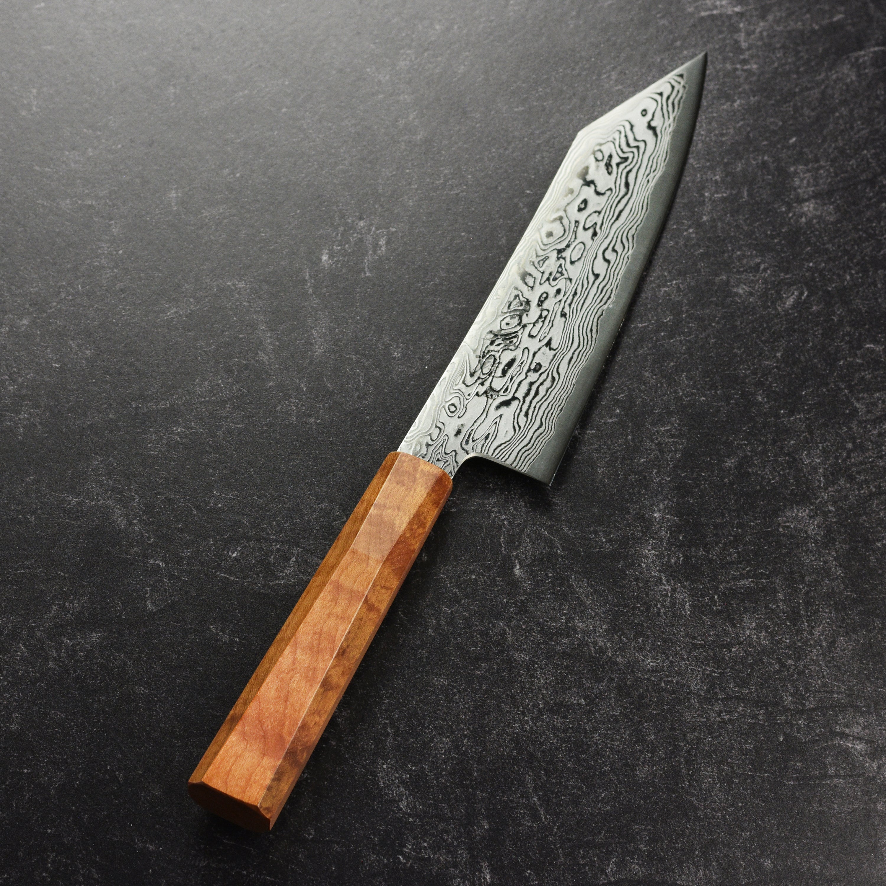 Professional chef using a Japanese knife to chop vegetables in a modern kitchen