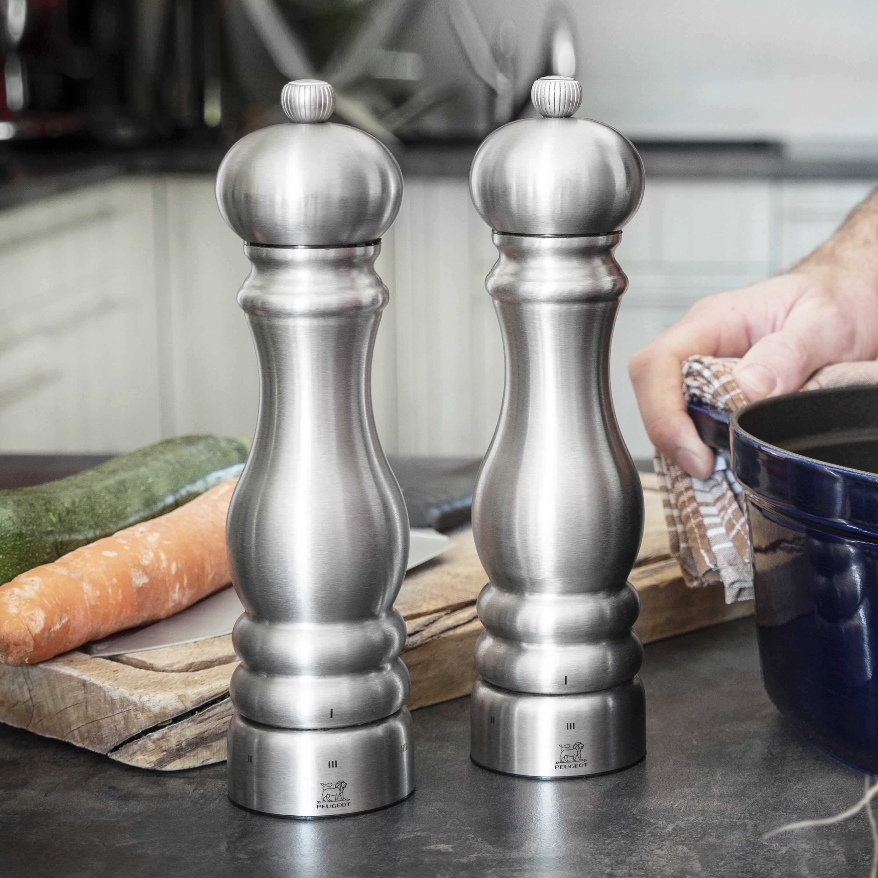 Peugeot Paris stainless steel salt and pepper mill set on kitchen counter, showing modern design and adjustable grind feature