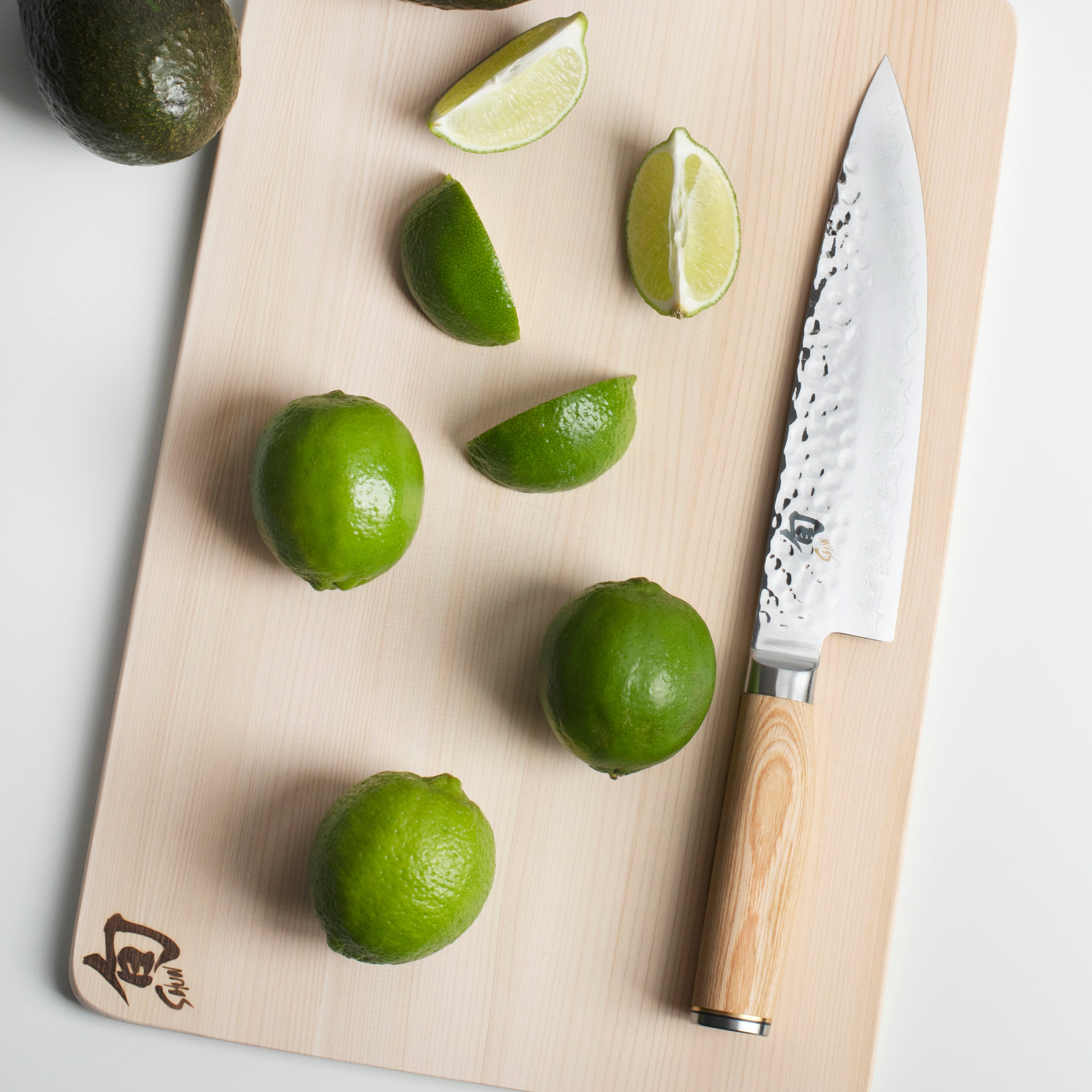 Shun Premier Blonde knife block set in use, slicing vegetables on a wooden cutting board.