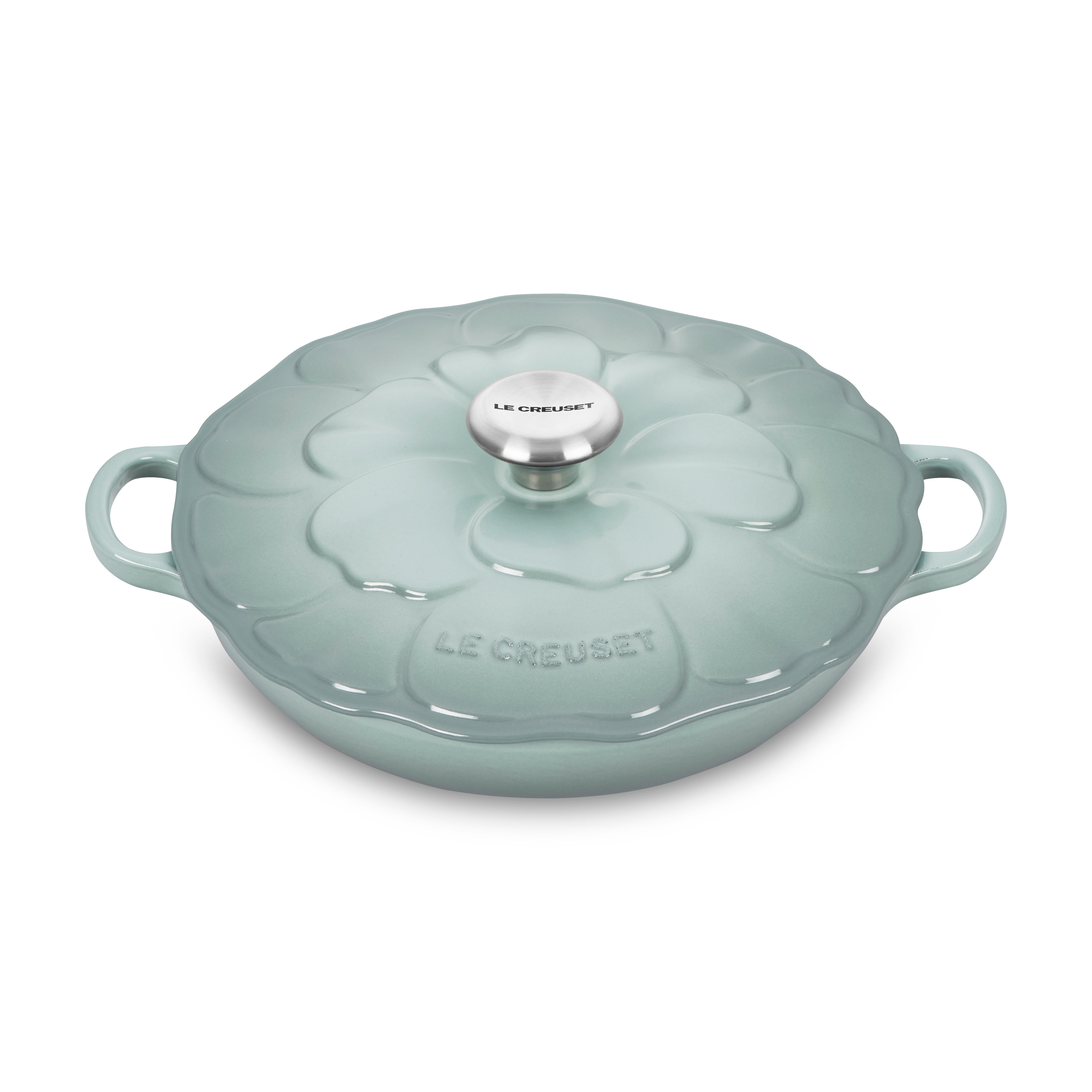 Side view of Sea Salt Petal Enameled Cast Iron Braiser with lid on a stove.