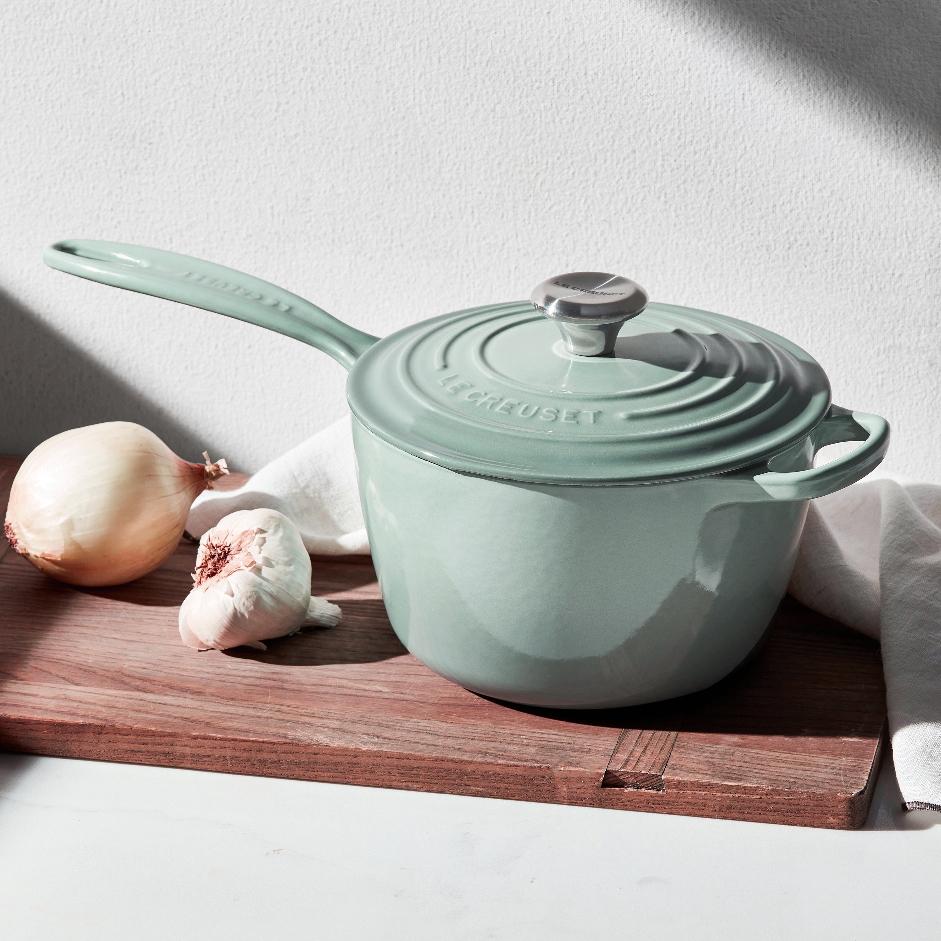 Le Creuset enameled cast iron saucepan from the side, highlighting the ergonomic handle and stainless steel knob.