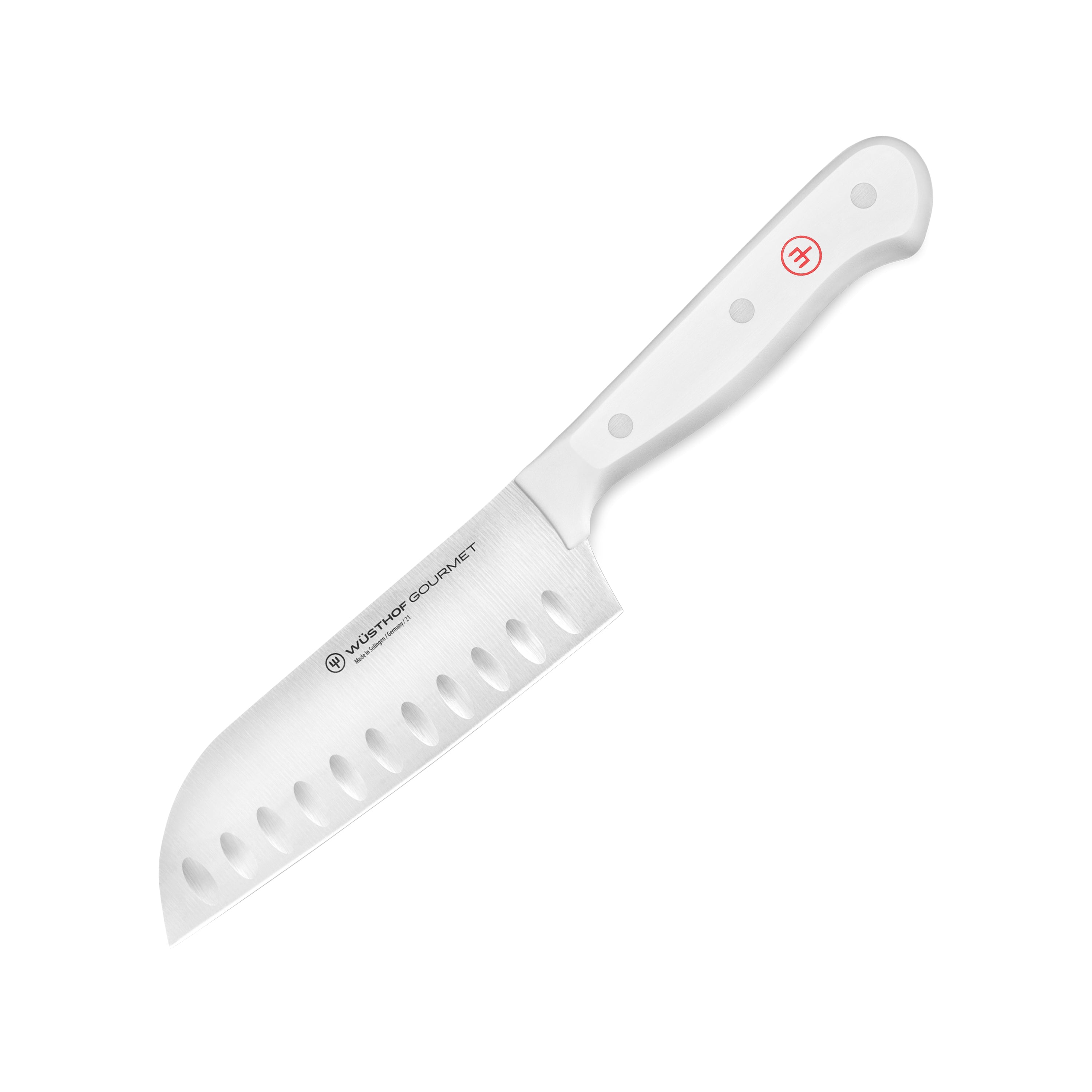 Wusthof Santoku knife with white handle cutting vegetables on a board.
