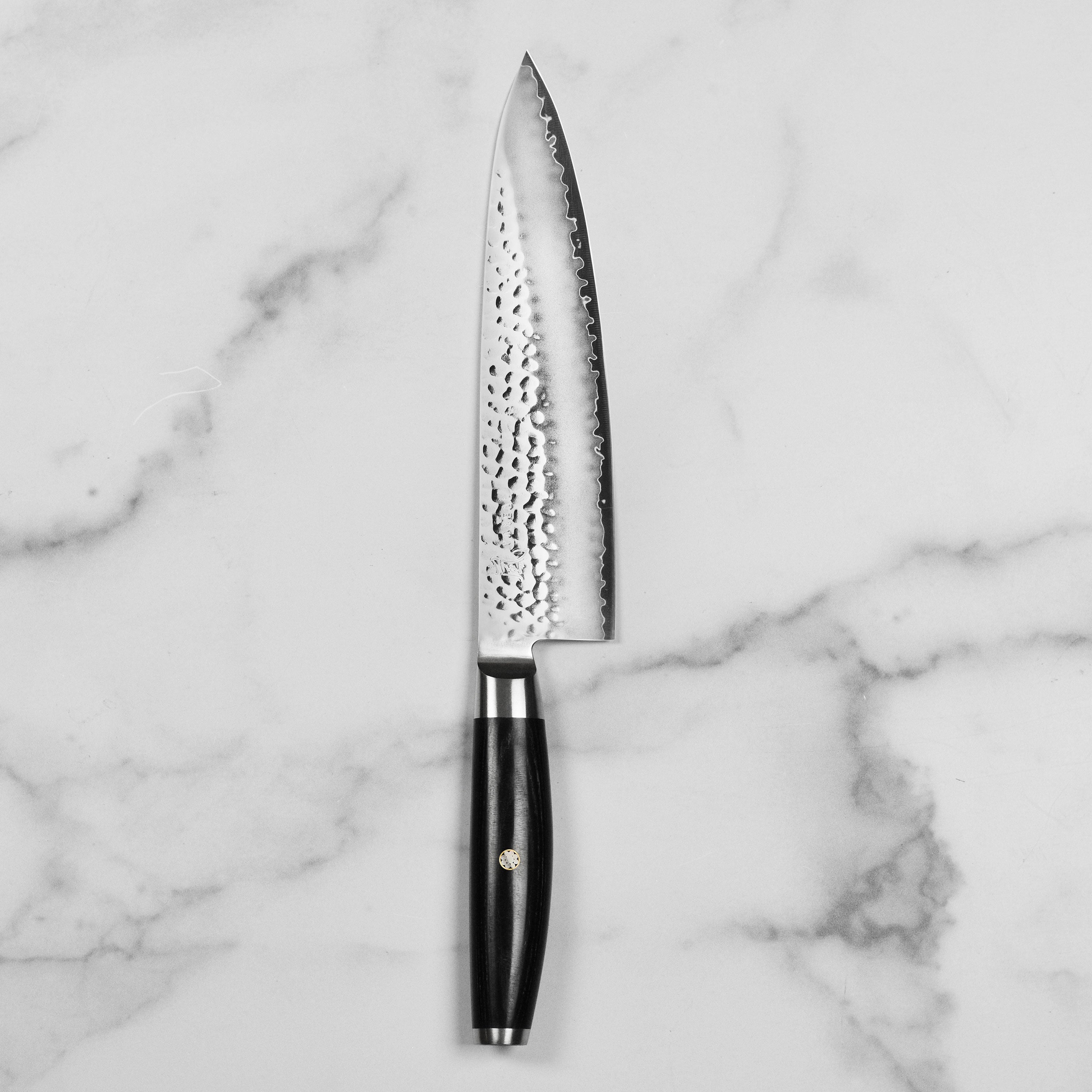 Chef using Yaxell Ketu Chefs Knife to chop vegetables in a bright kitchen.