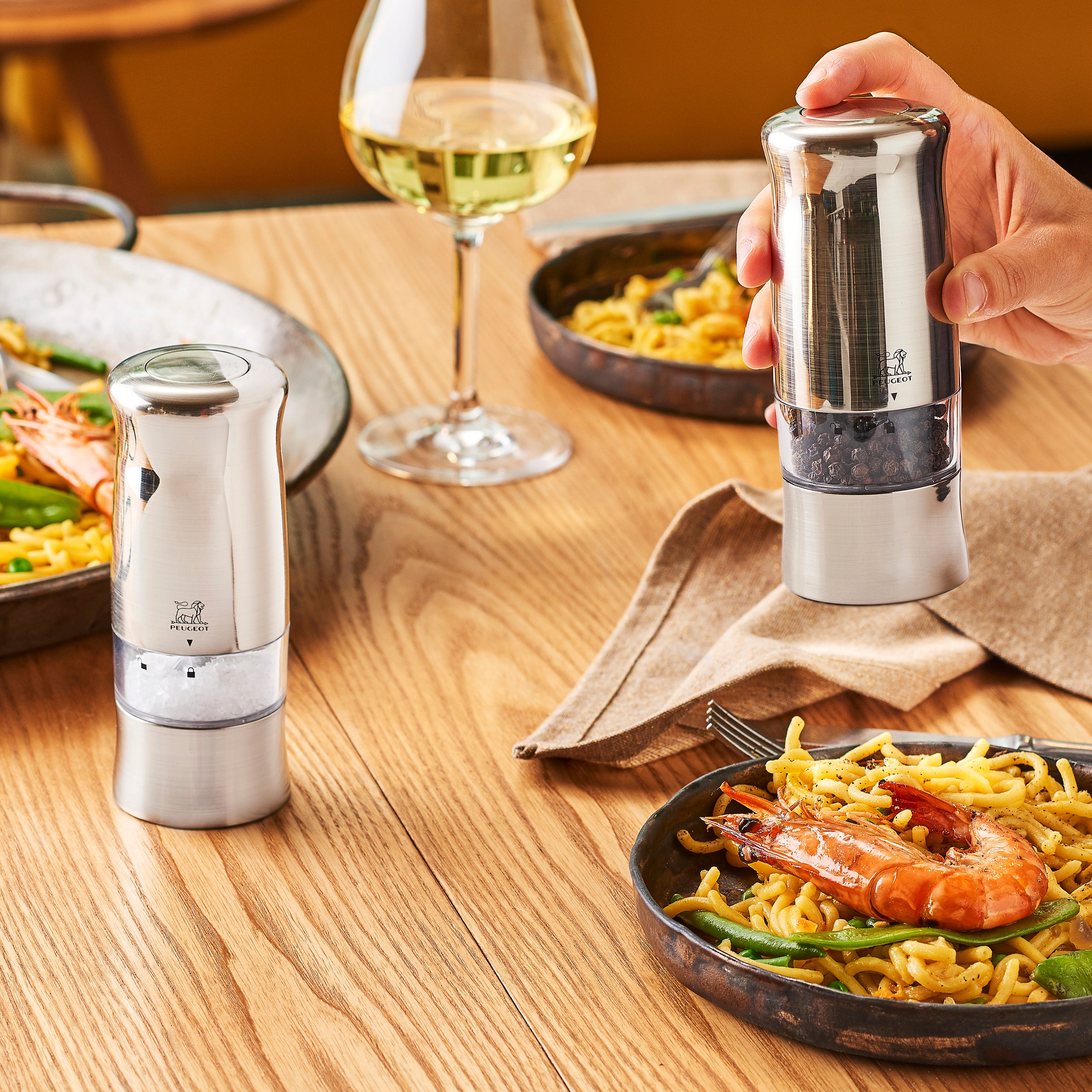 Elegant Peugeot Zeli electric salt mill with a mirrored chrome finish on a dining table