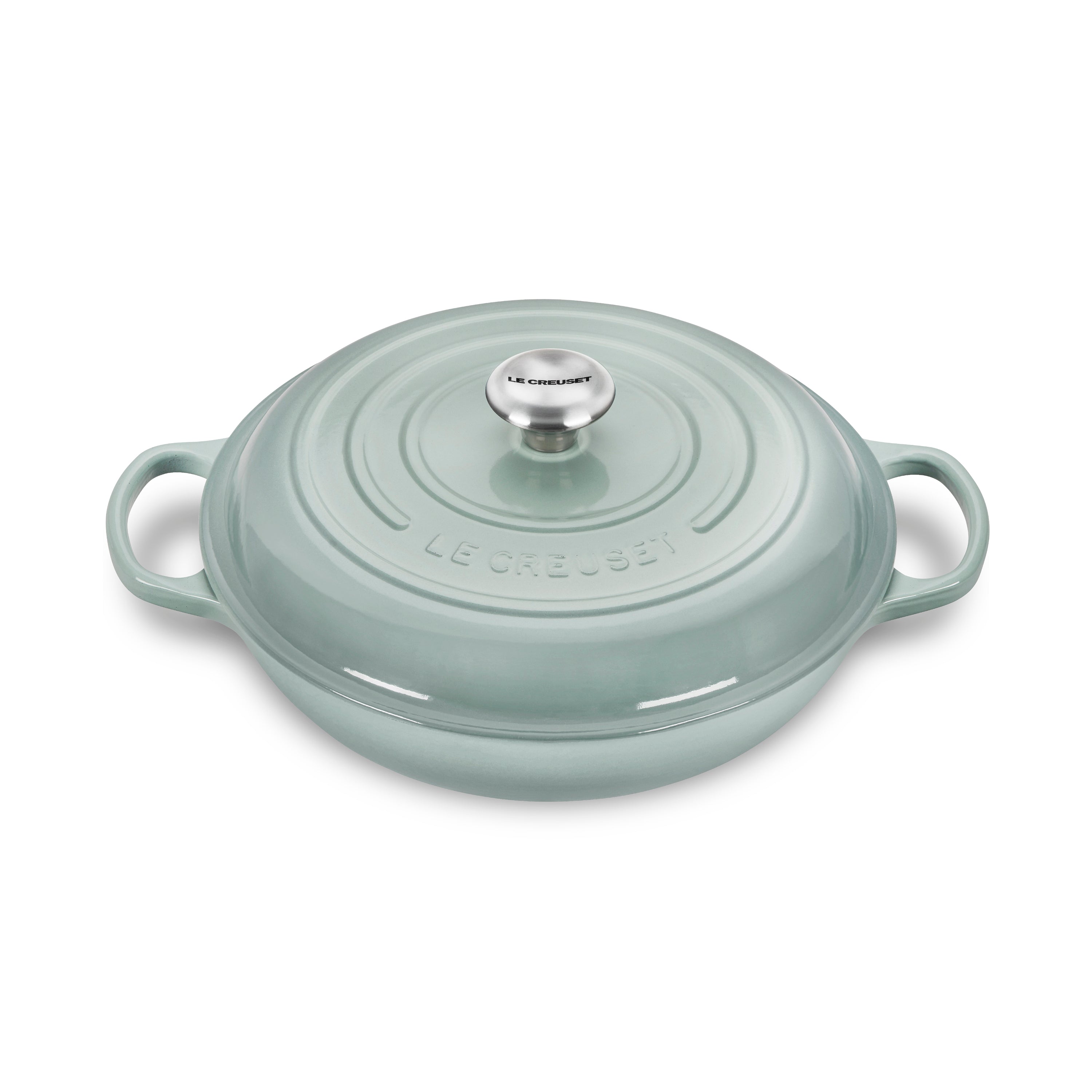 Le Creuset cast iron braiser with lid on stovetop, showcasing its durable enamel surface