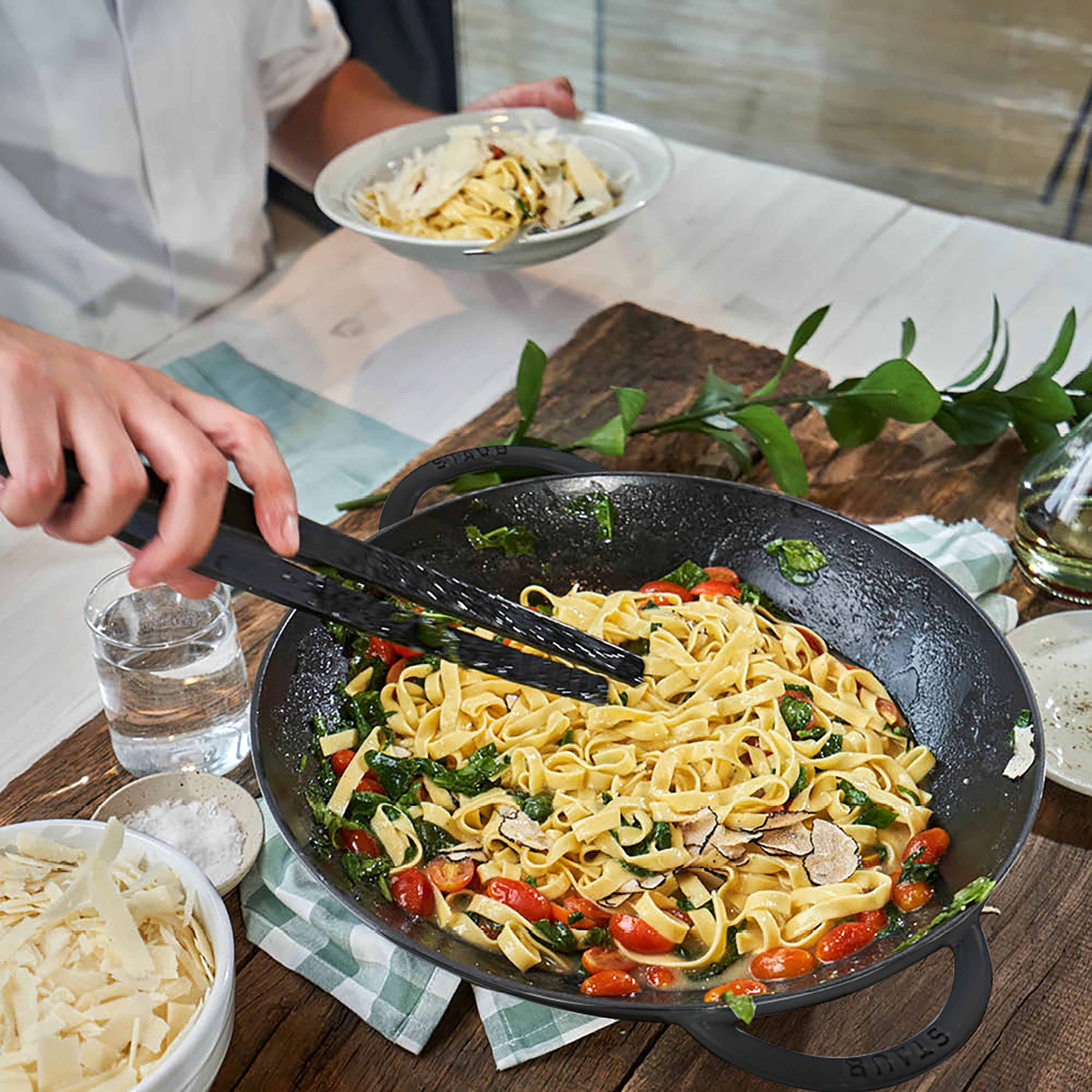 Close-up of Staub 14-inch matte black enameled wok with glass lid, showing textured interior and sleek design