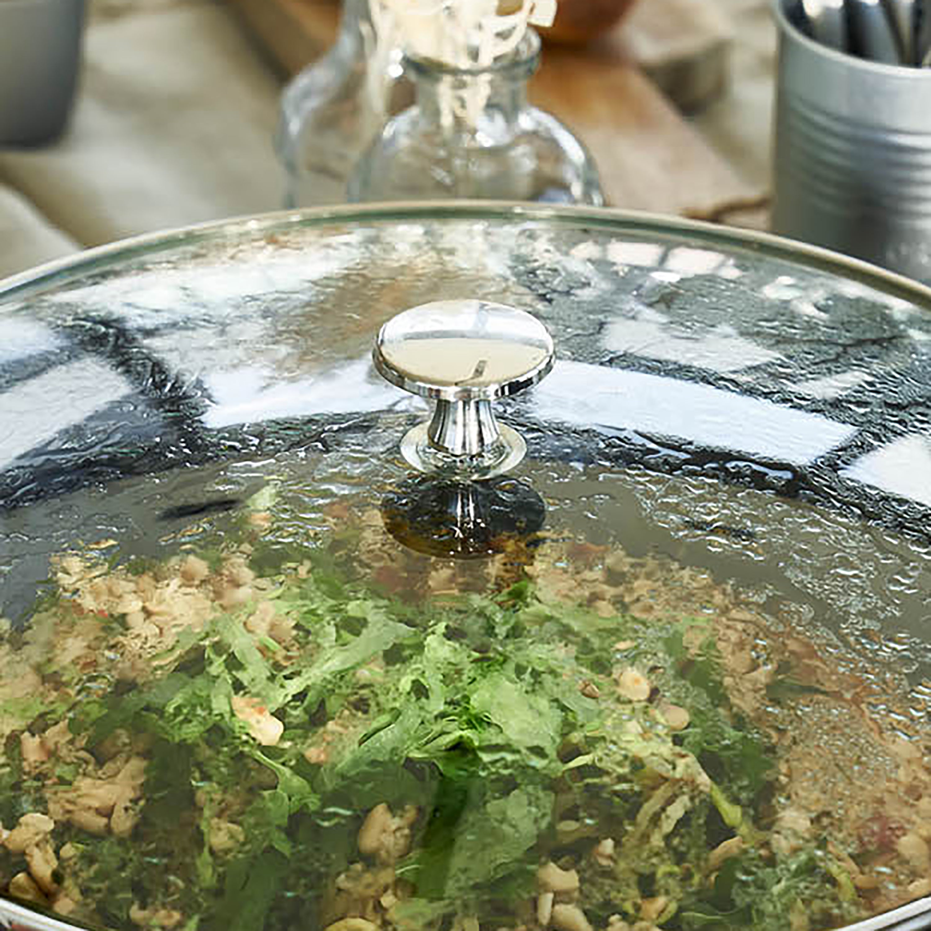 Close-up of Staub 14-inch matte black enameled wok with glass lid, showing textured interior and sleek design