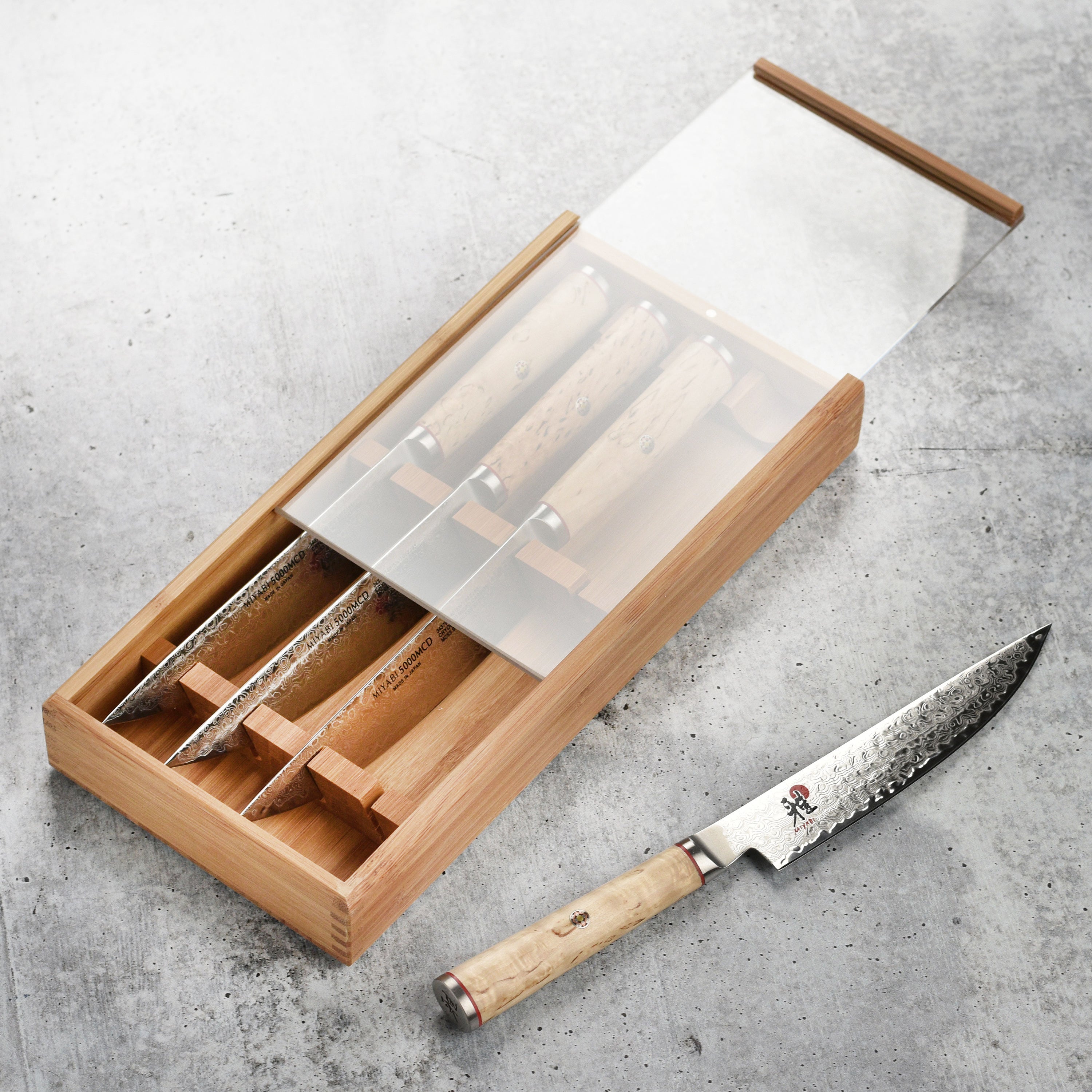 Close-up of Miyabi Damascus steel blade with katana edge against a wooden cutting board