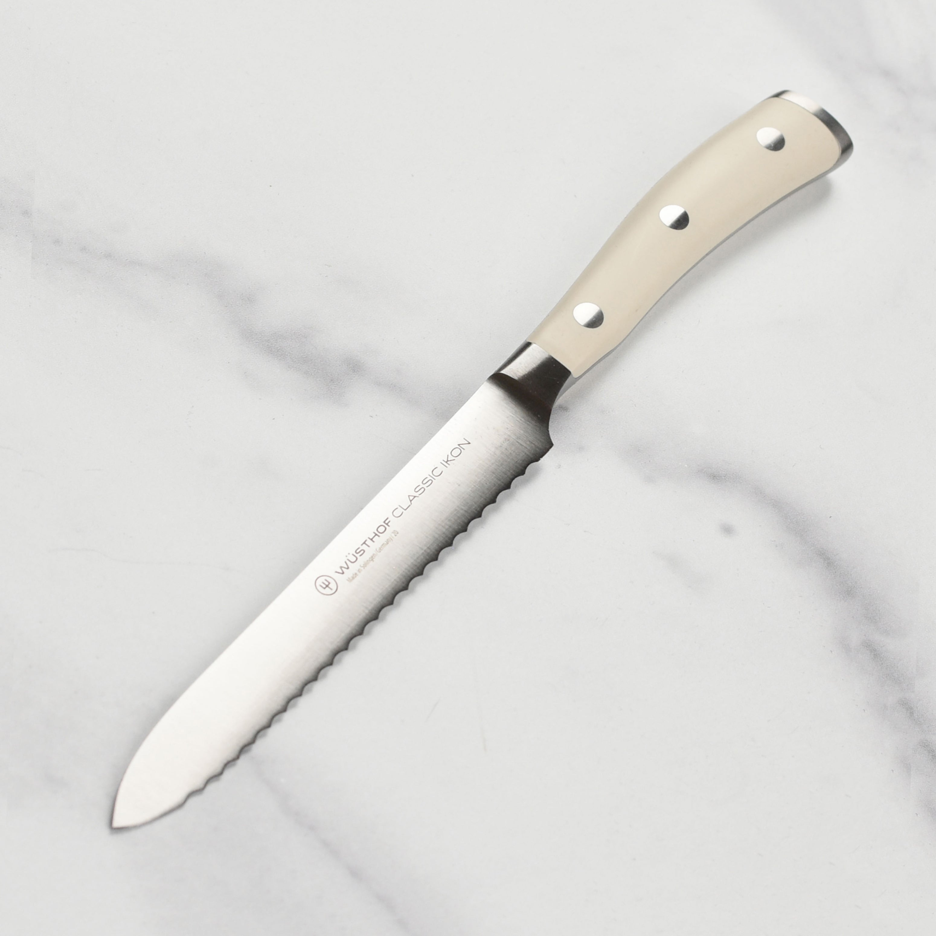 Wusthof Classic Ikon Creme serrated utility knife showcasing its sharp blade and ergonomic handle for precise slicing