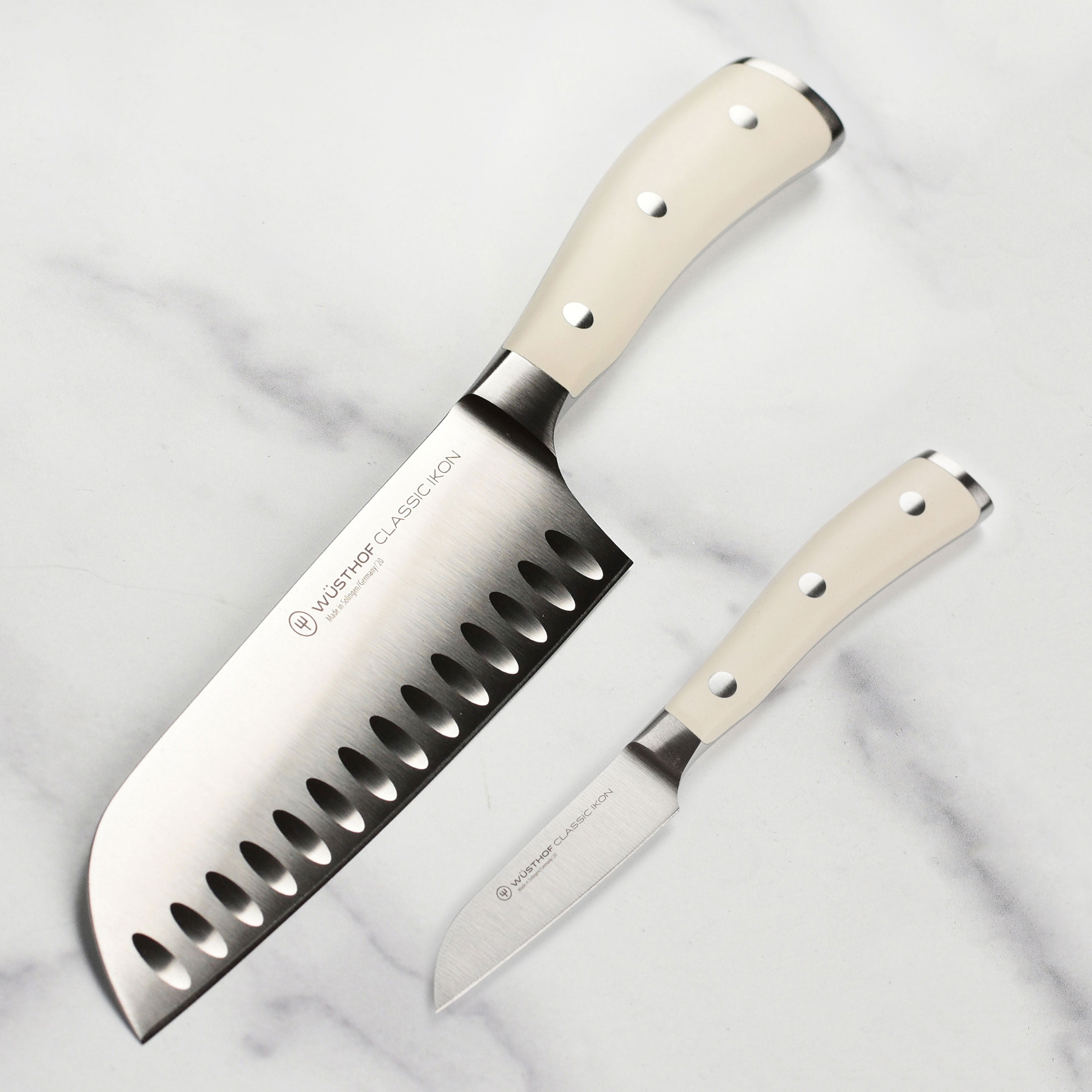 Overhead view of both knives in the set, showcasing the creme handles and forged blade quality ideal for refined kitchen knives.