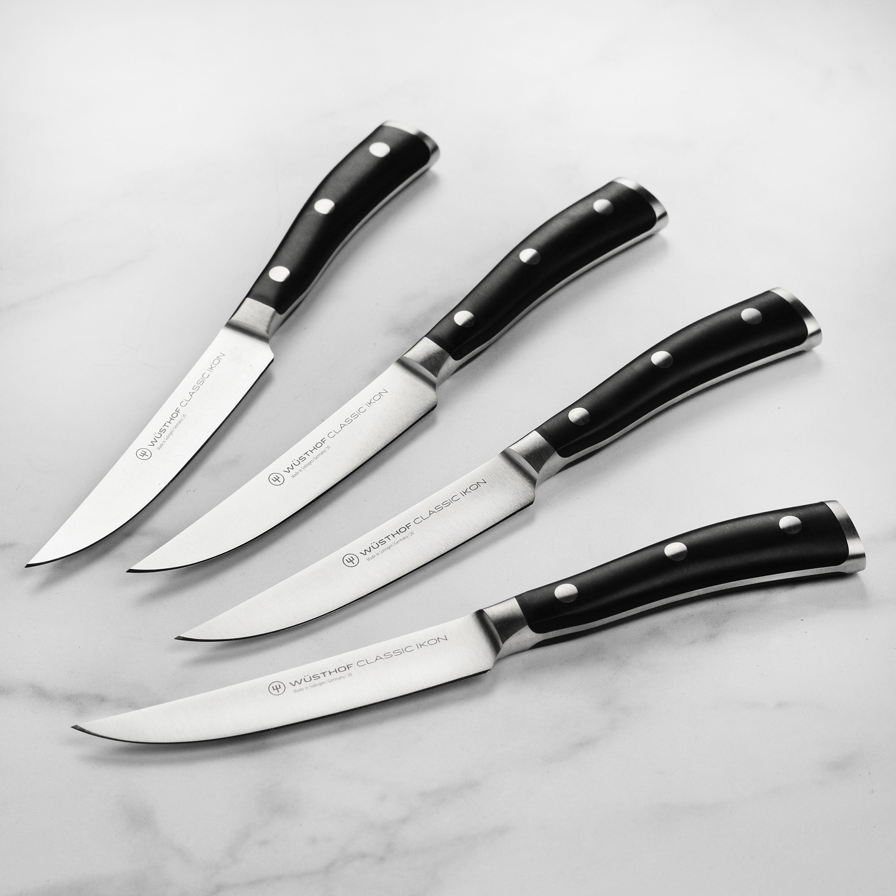 Wusthof Classic Ikon steak knives with black handles on a cutting board