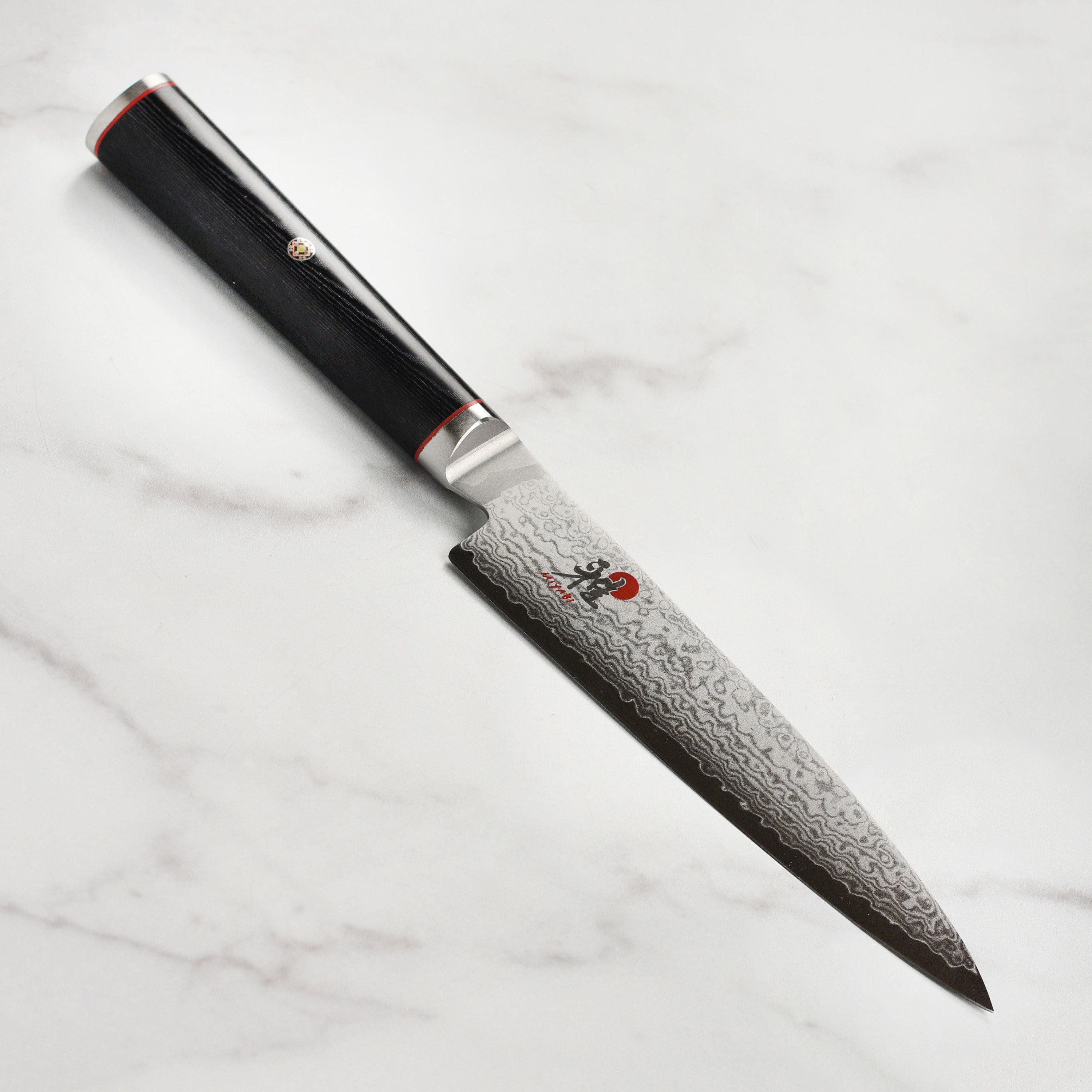 Close-up of the blade of the Miyabi Kaizen 6-inch utility knife highlighting the Damascus pattern.