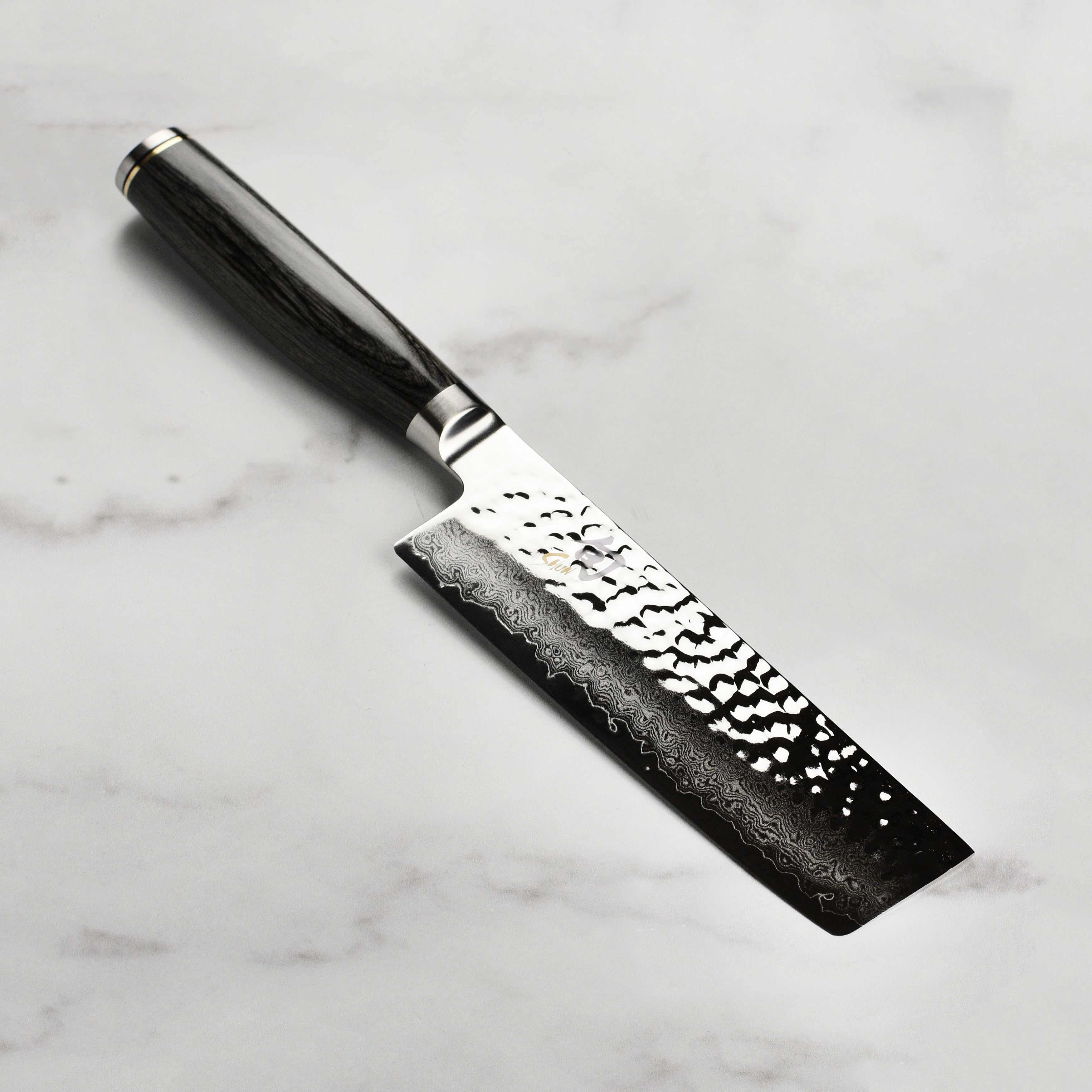 Close-up view of Shun Premier Nakiri Knife showcasing its Damascus blade and hammered finish.