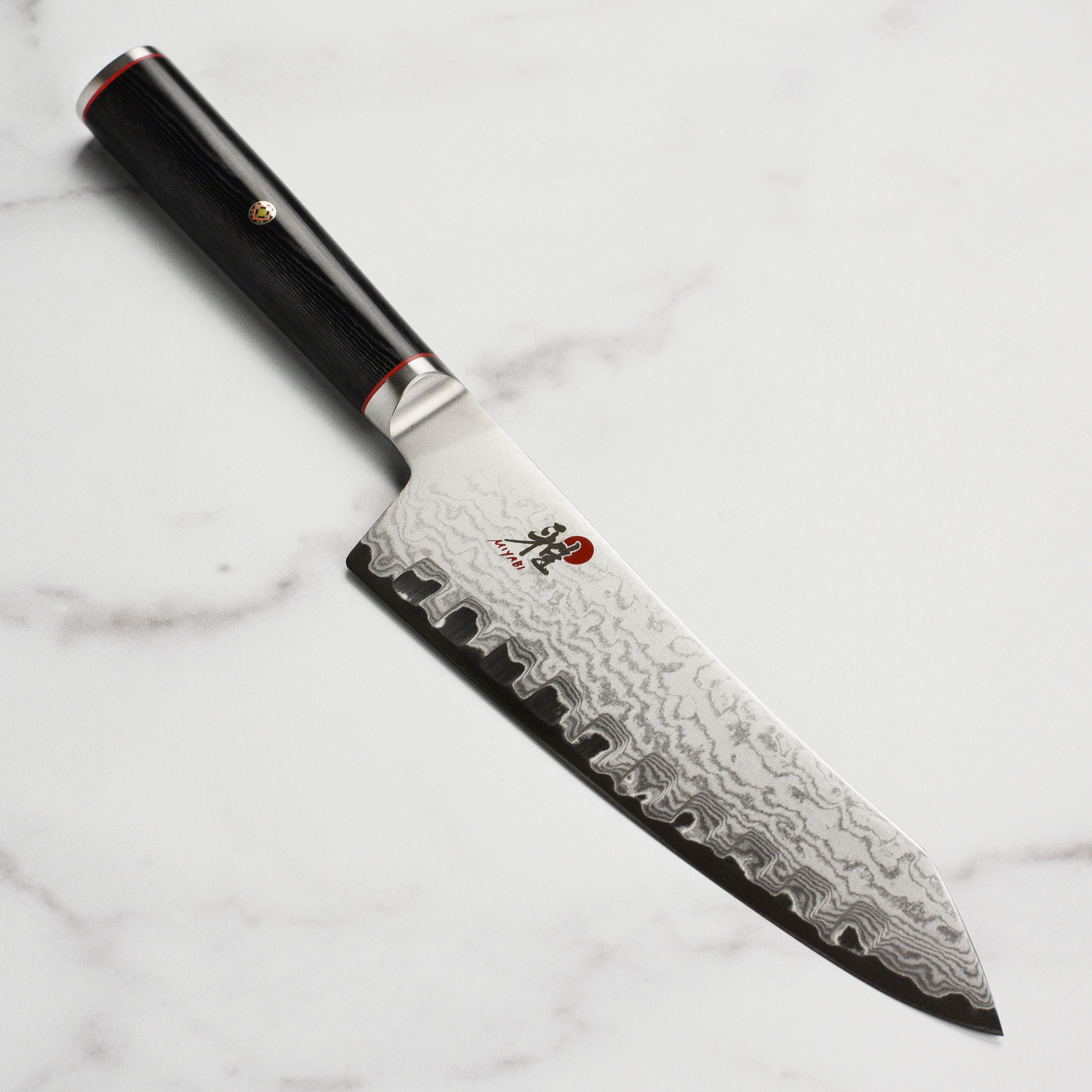 Miyabi 7-inch Santoku knife showcasing its Damascus steel blade and Micarta handle from an angle