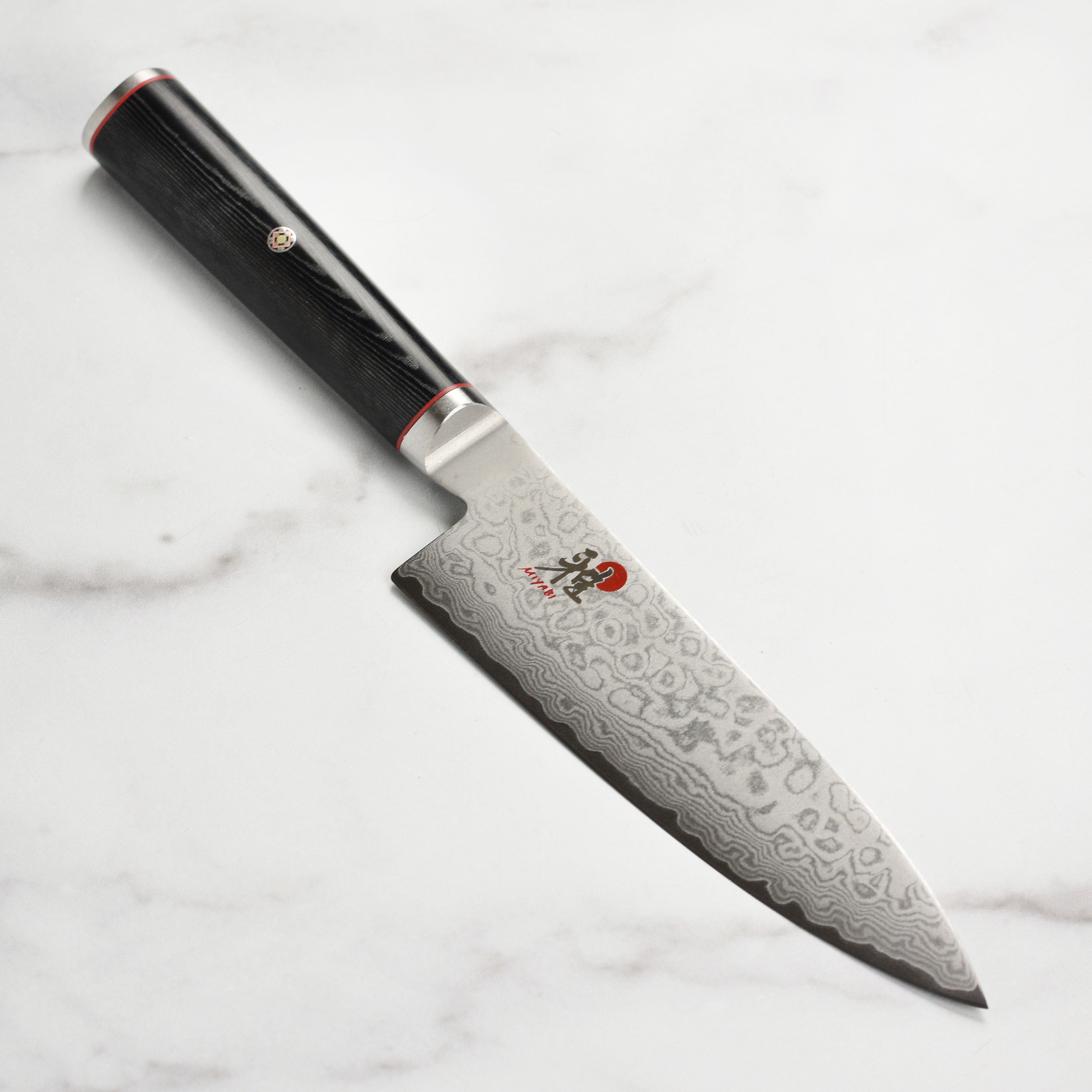 Close-up view of the Miyabi Kaizen 6-Inch Chef's Knife blade highlighting the Damascus steel pattern.