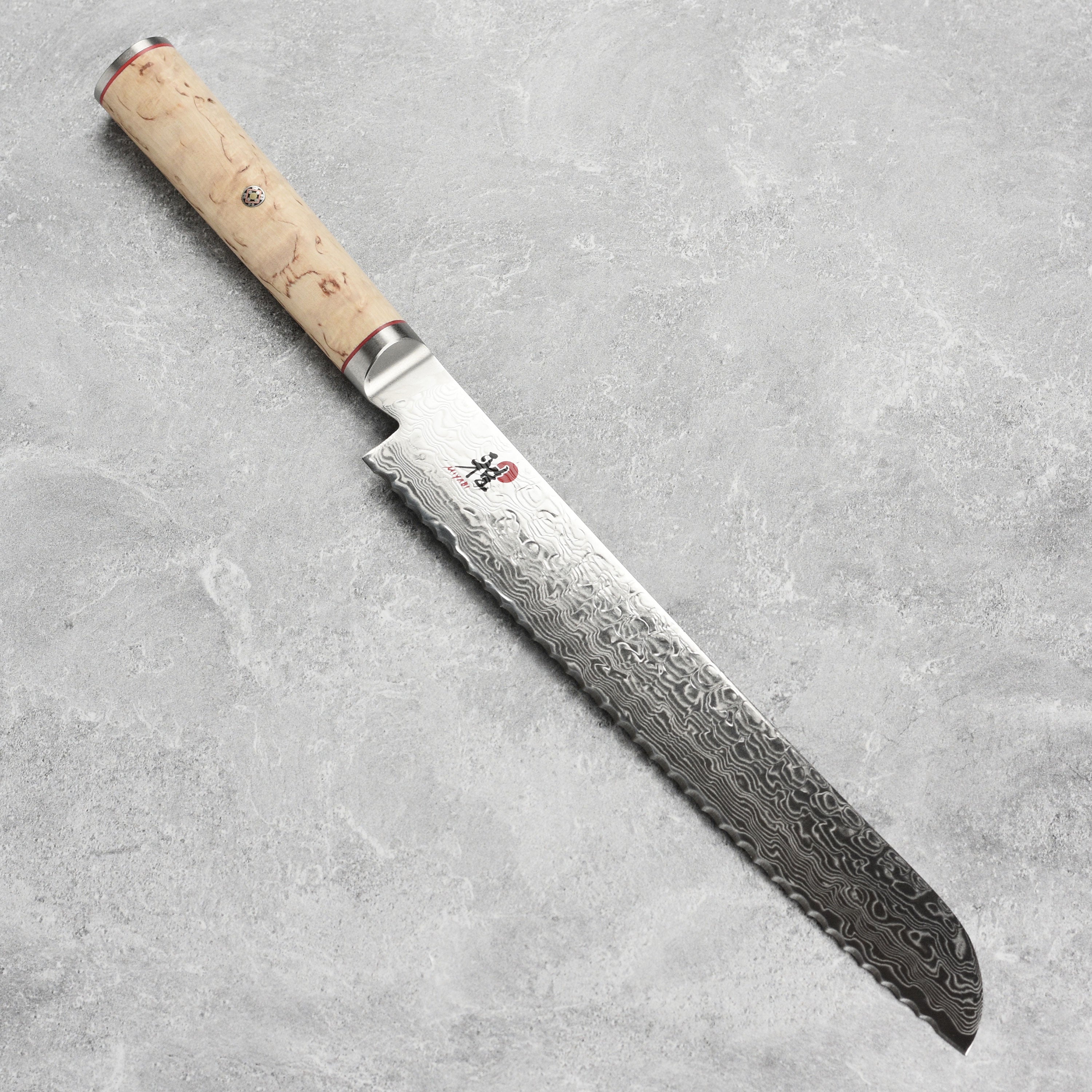 Close-up of the Miyabi Birchwood Japanese Bread Knife highlighting the Damascus blade and Karelian Birchwood handle.