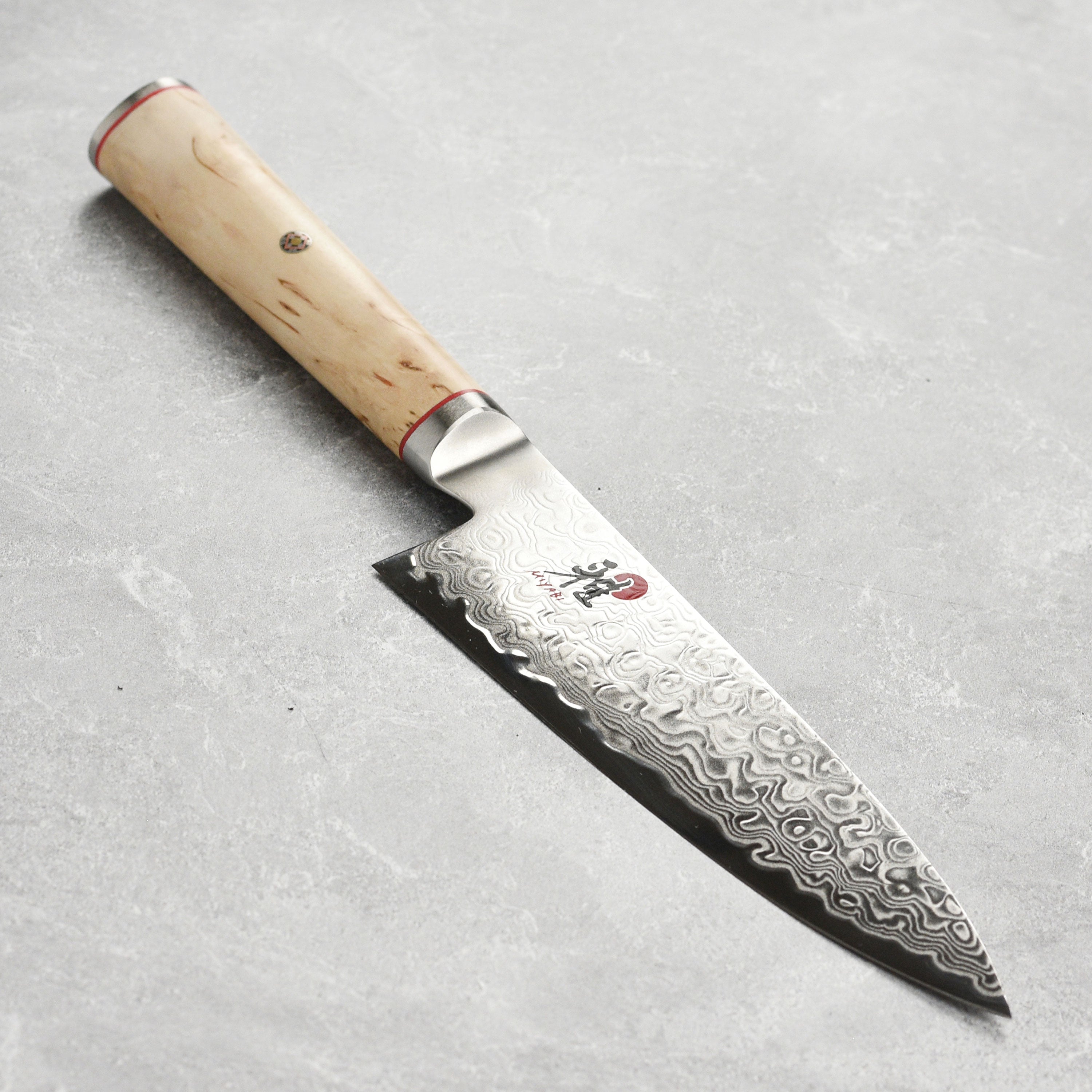 Miyabi Birchwood SG2 chef's knife displayed on a wooden cutting board, highlighting its elegant Damascus pattern.