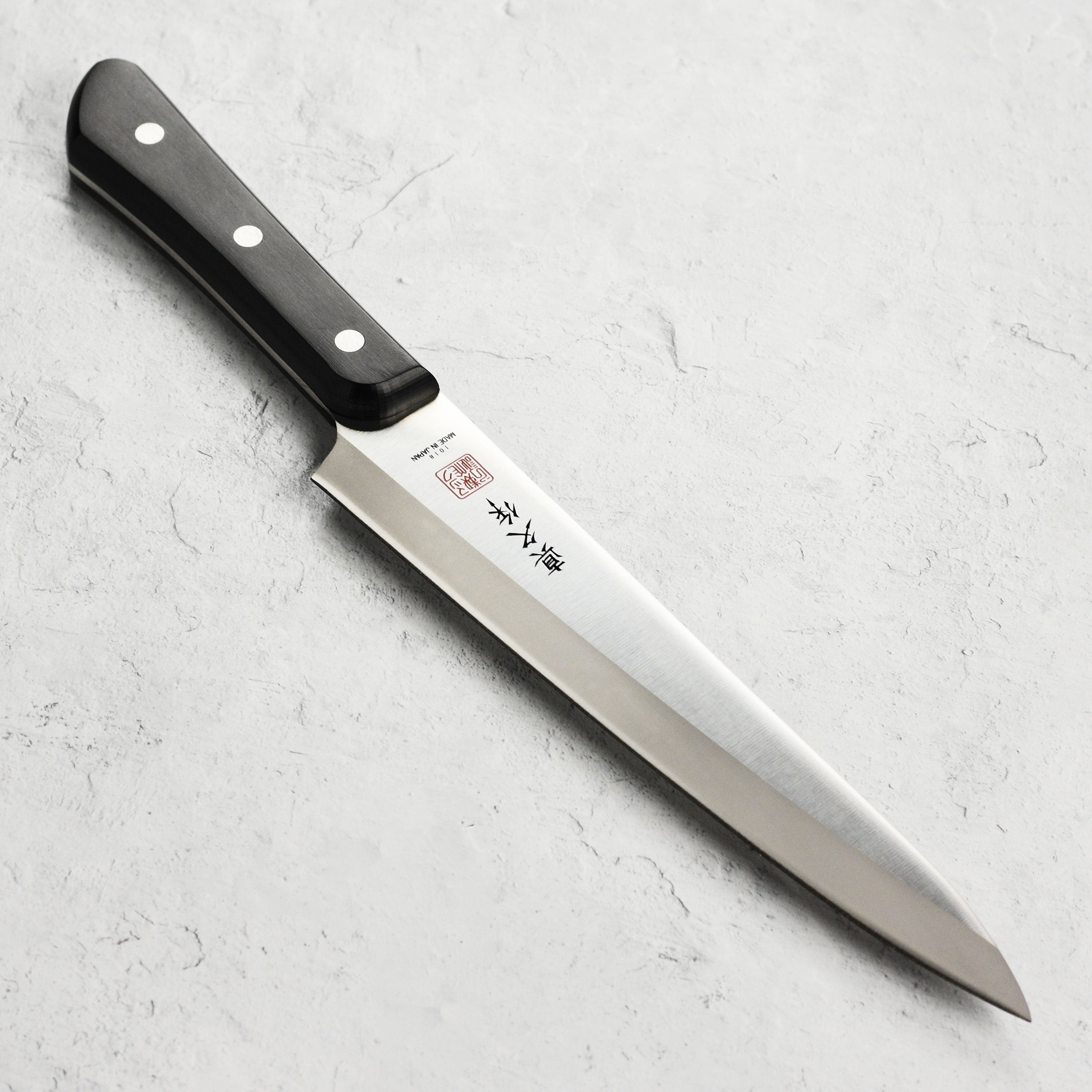 Close-up of the MAC Superior carving knife highlighting its thin blade and Pakkawood handle.