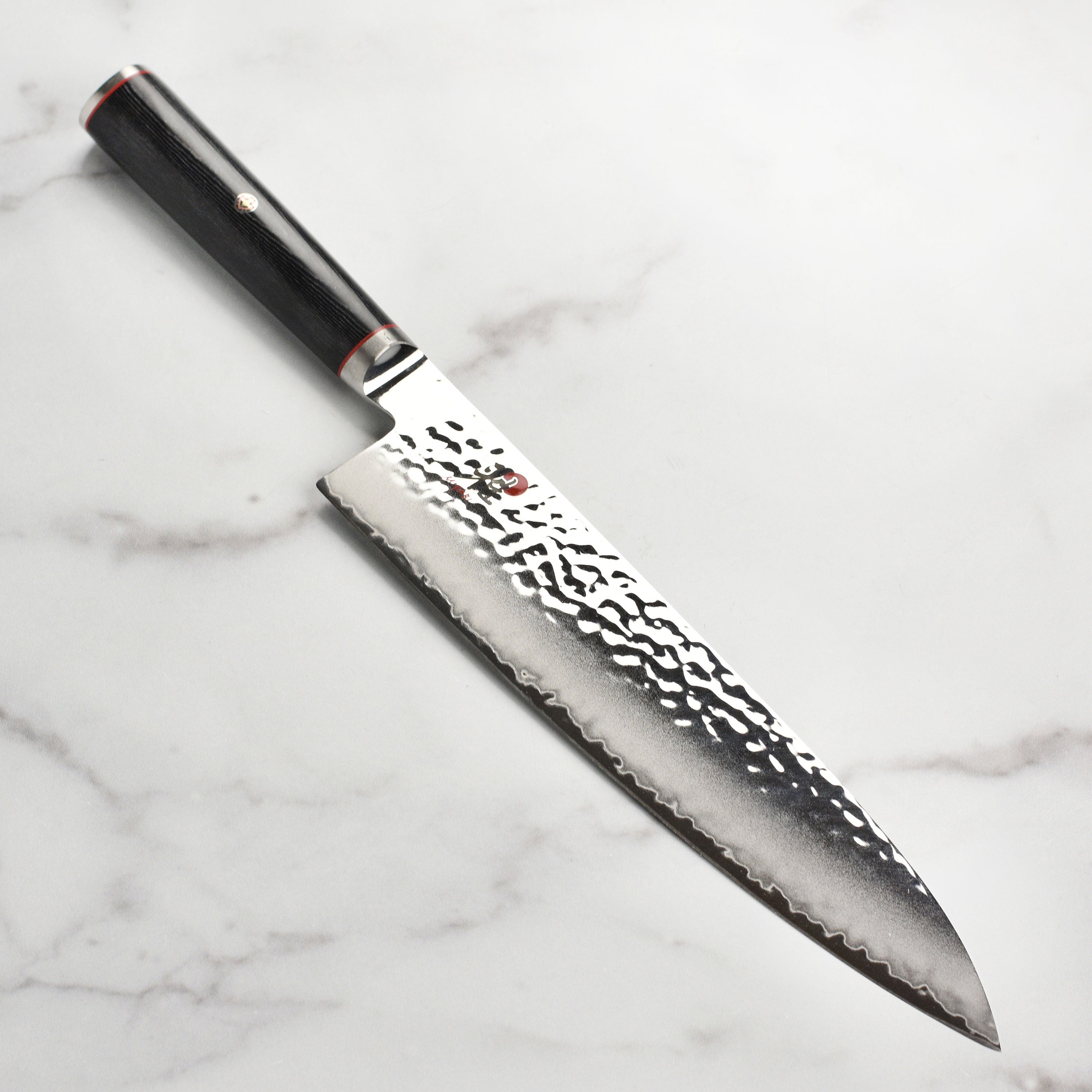 Miyabi Mizu SG2 9.5-inch Japanese chef's knife with Damascus textured finish on a cutting board