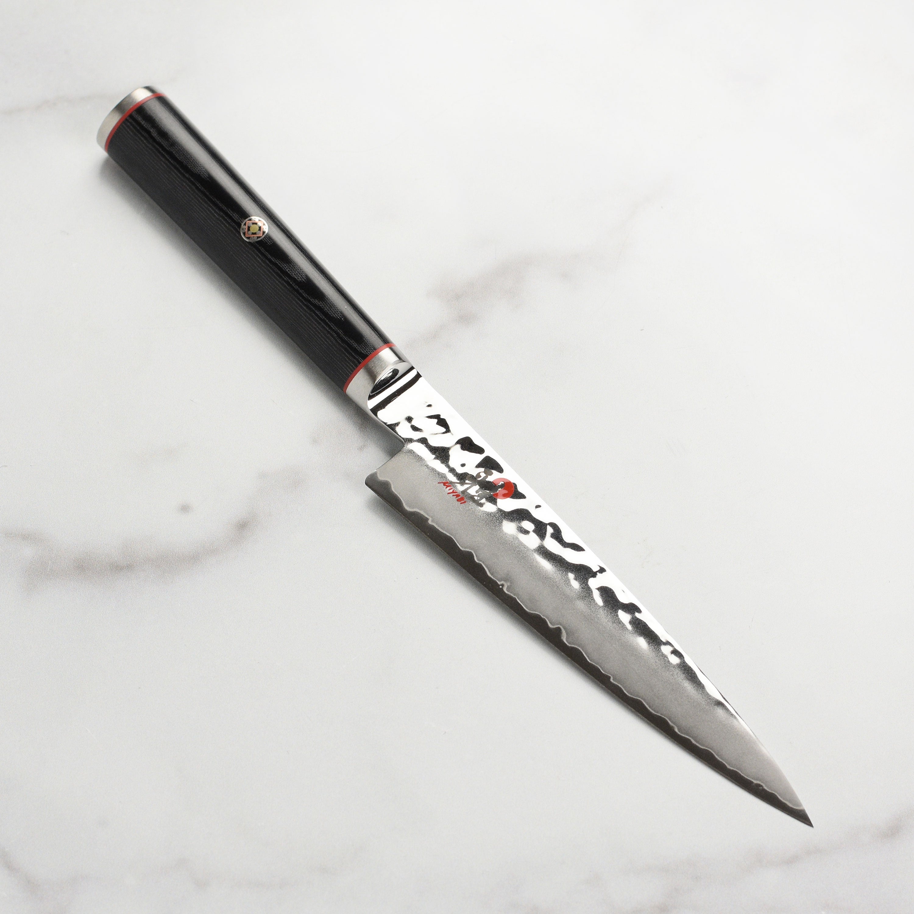 Close-up view of the Miyabi Mizu SG2 utility knife highlighting its sharp blade and Damascus texture.