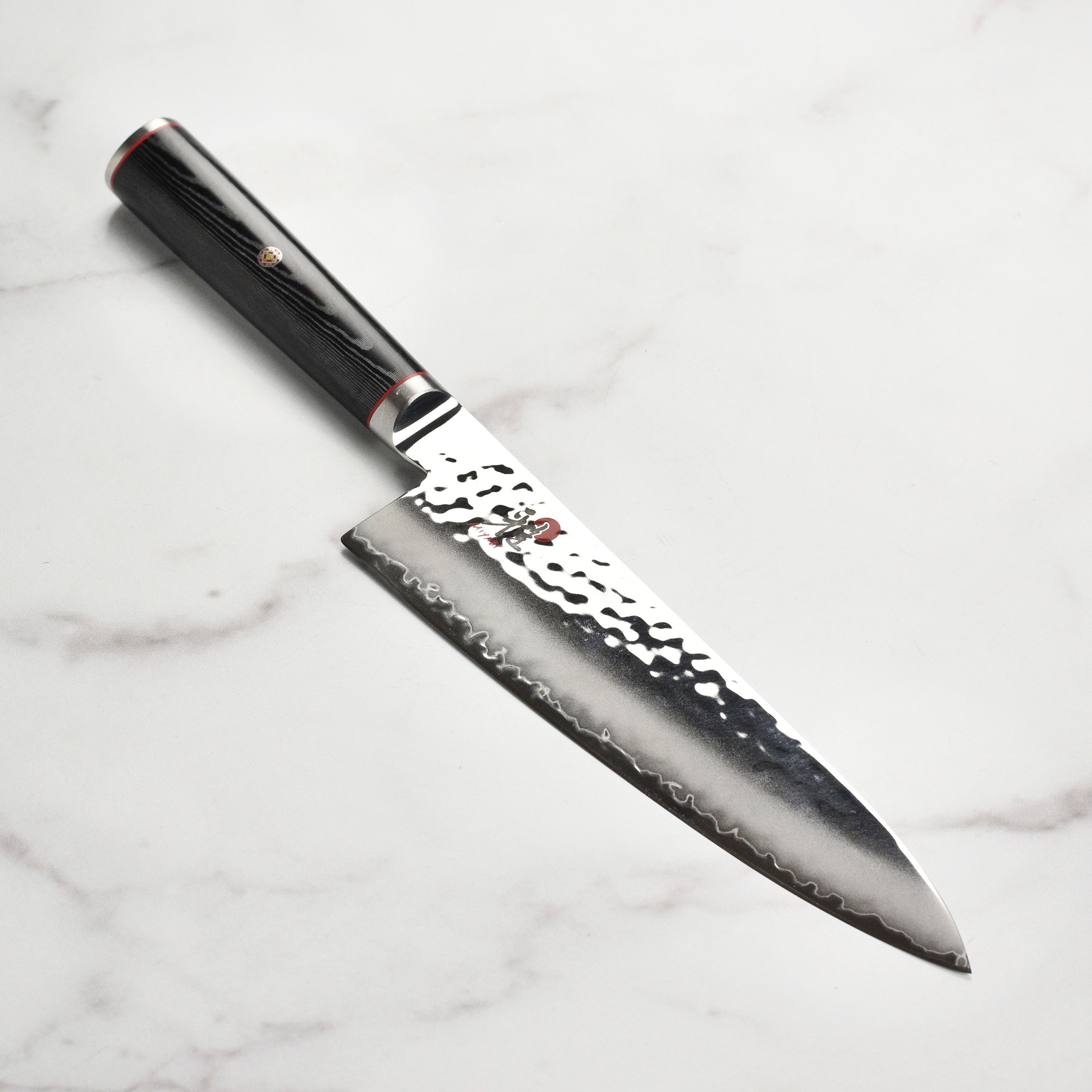 Close-up of the Miyabi Mizu SG2 chef's knife blade, highlighting the Damascus finish and micro carbide steel.