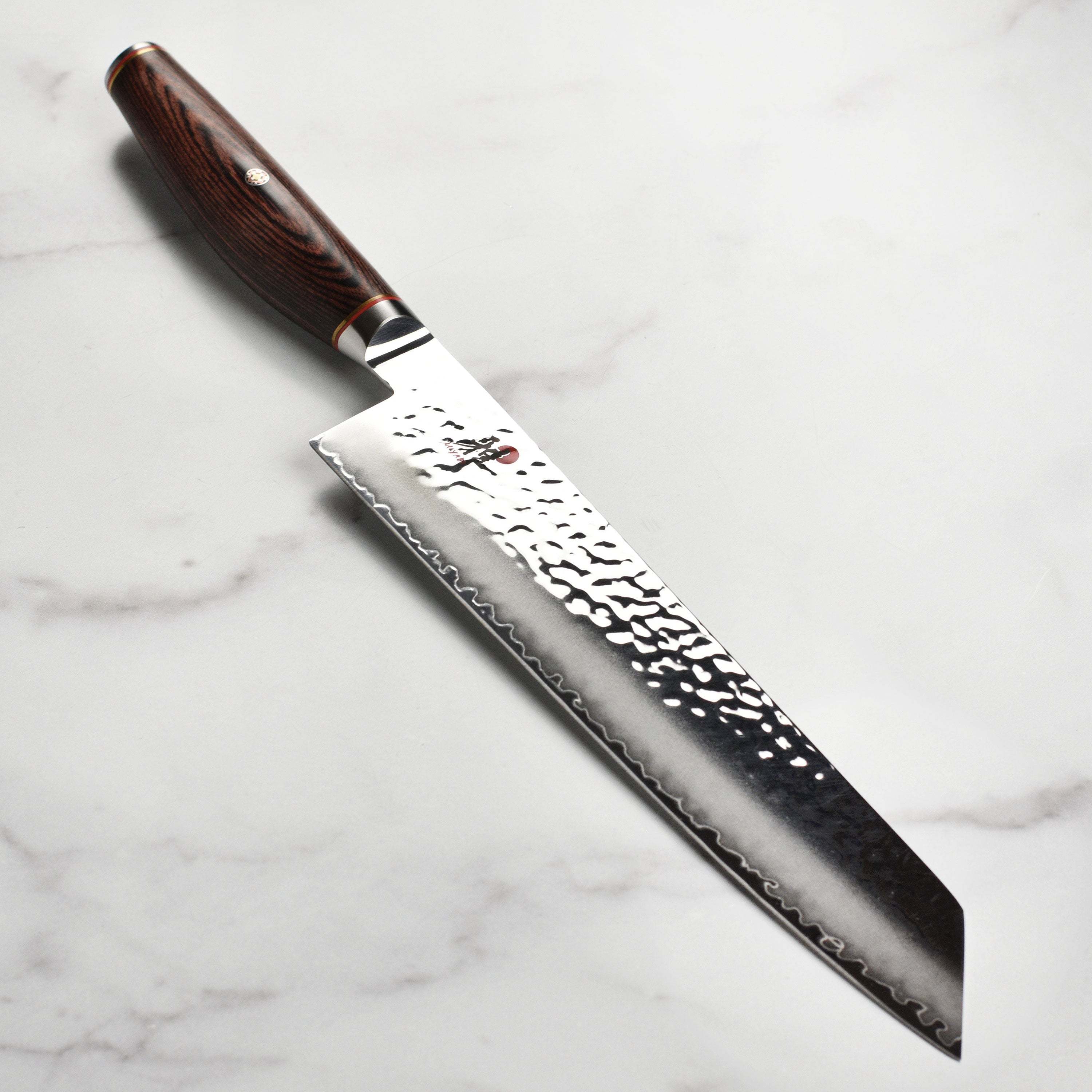 Close-up of the Miyabi Artisan SG2 Kiritsuke knife highlighting its Damascus steel blade and craftsmanship.