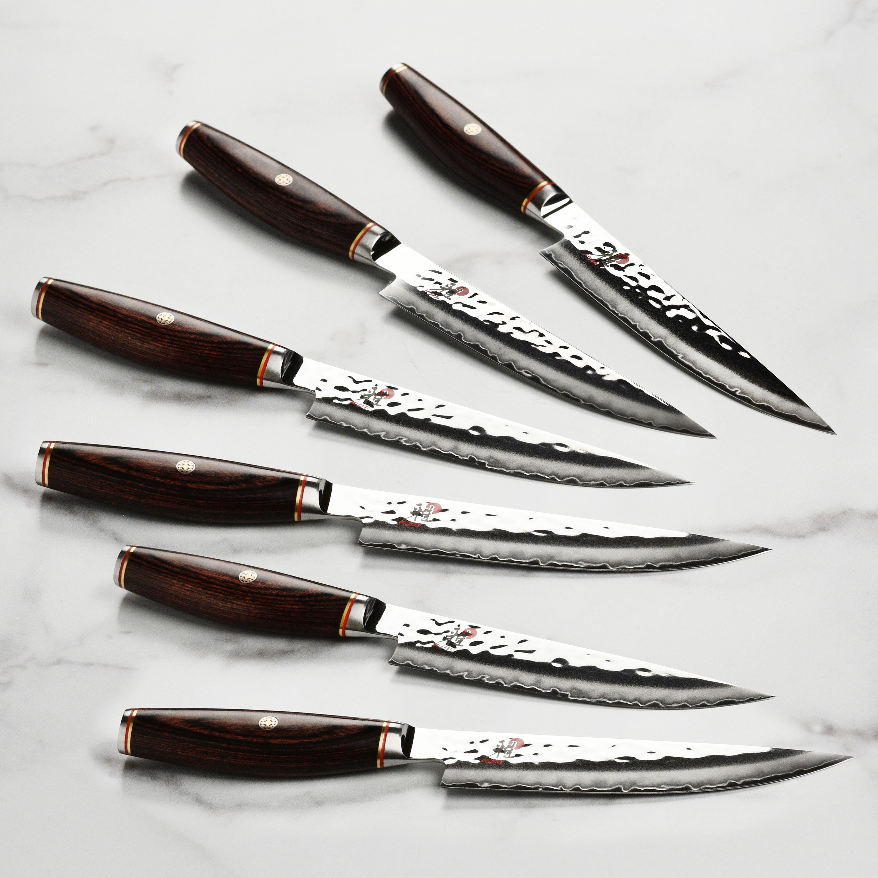 Miyabi Artisan SG2 steak knives showcasing the hammered Damascus finish from a side angle.