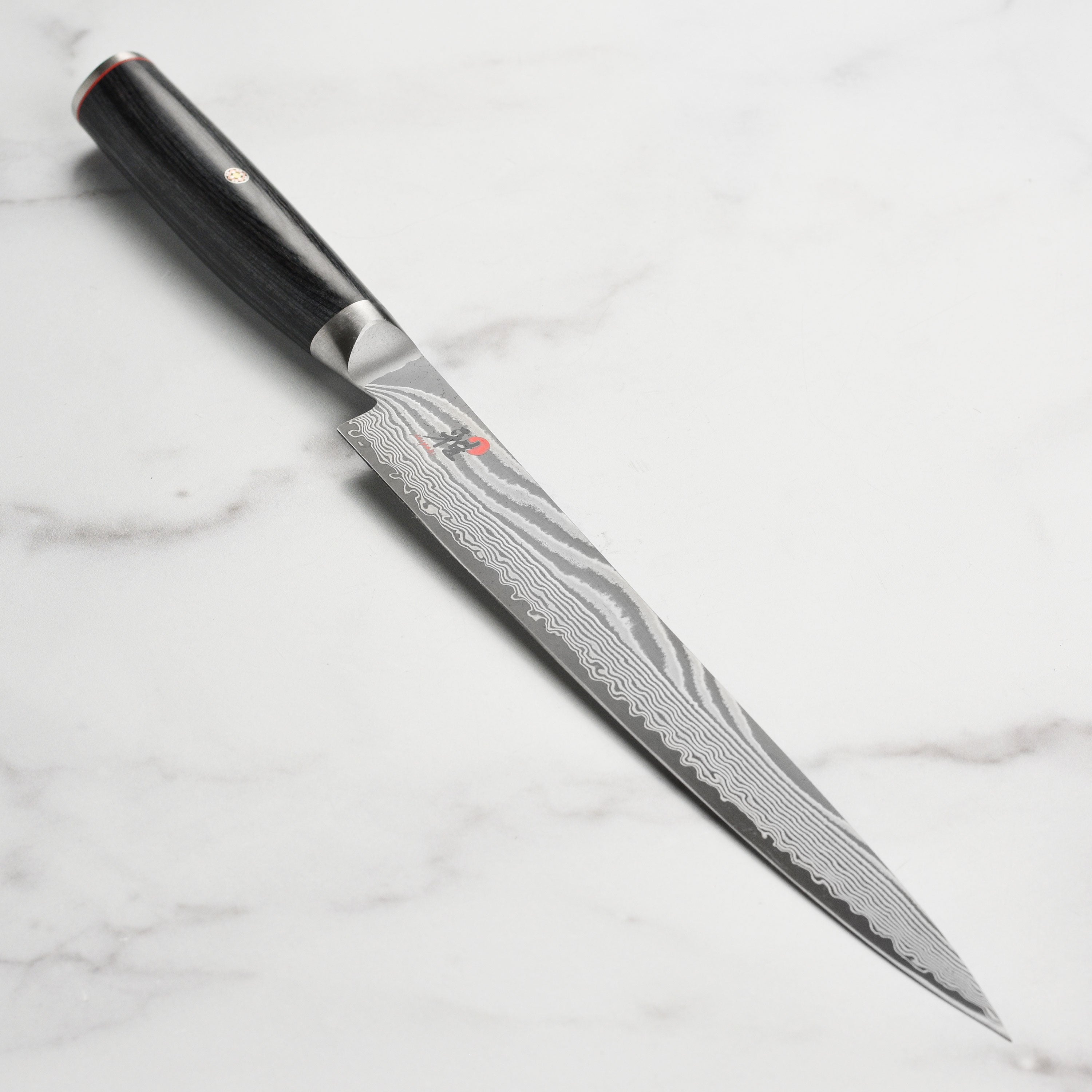Close-up of Miyabi Kaizen II Damascus slicing knife blade showing intricate pattern