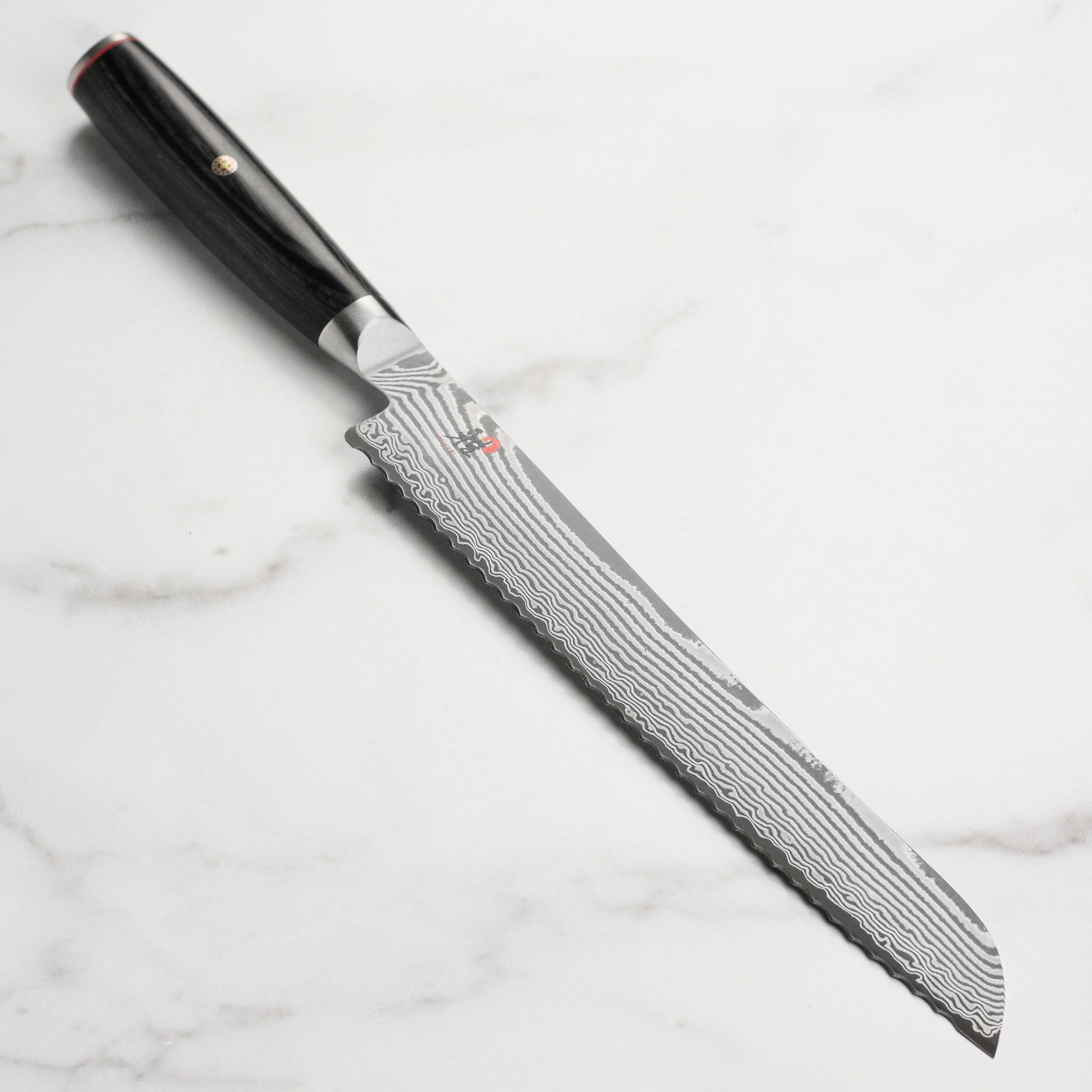 Miyabi Kaizen II 9-inch Damascus bread knife with intricate Damascus pattern and pakkawood handle