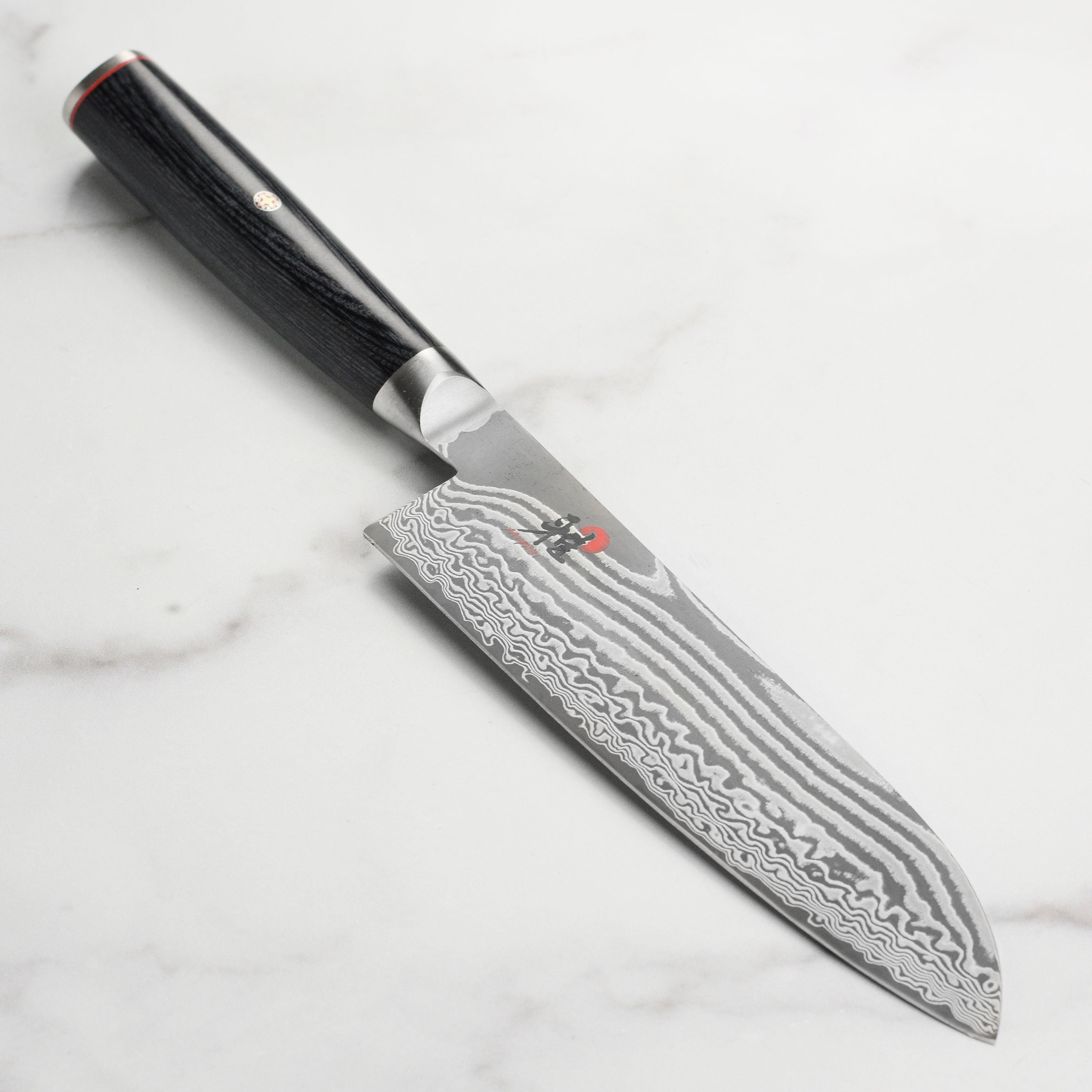 Miyabi Kaizen II Santoku knife showcasing its Damascus pattern and sharp blade angle.