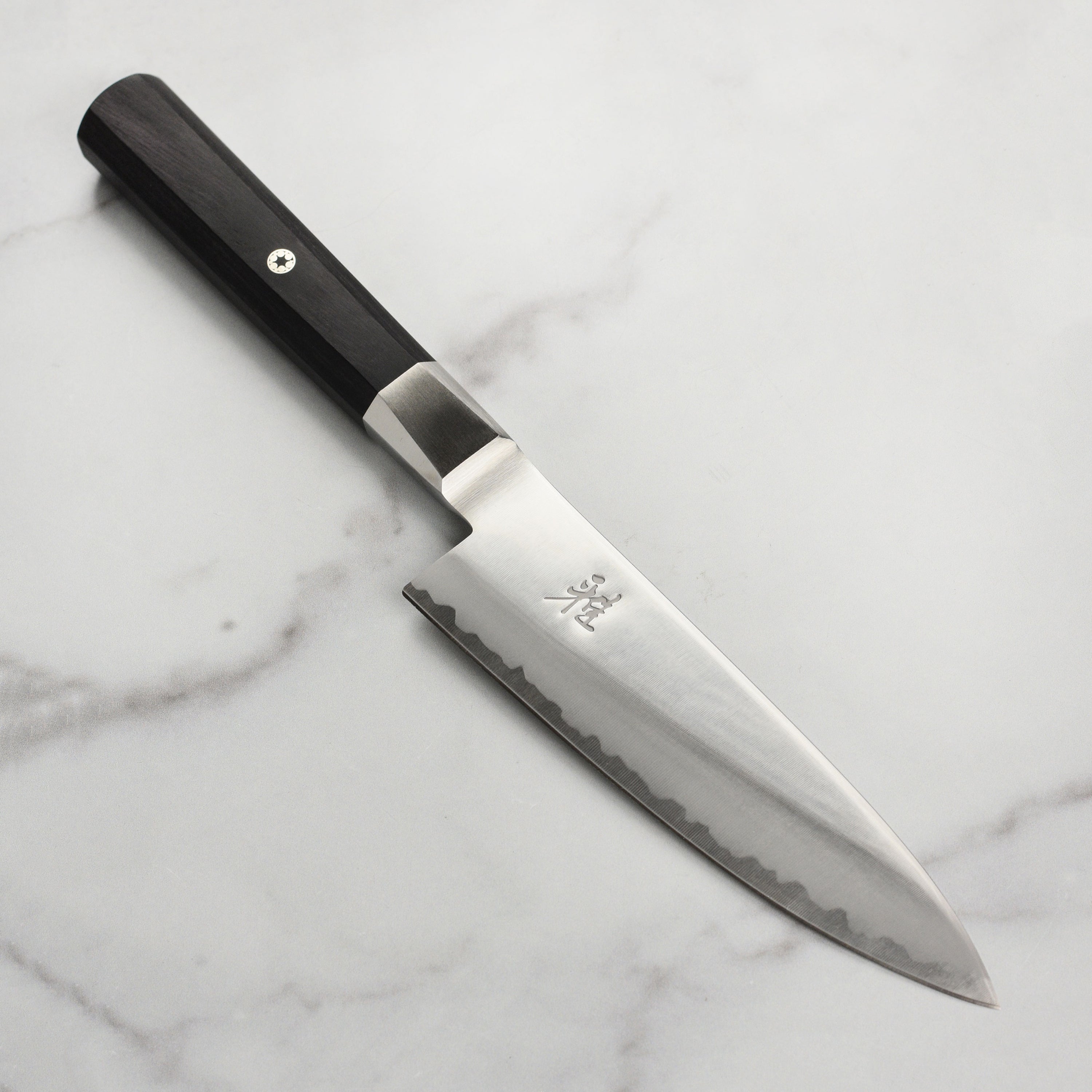 Miyabi Koh 6 inch chef's knife, angled view, highlighting the sharp edge and craftsmanship.