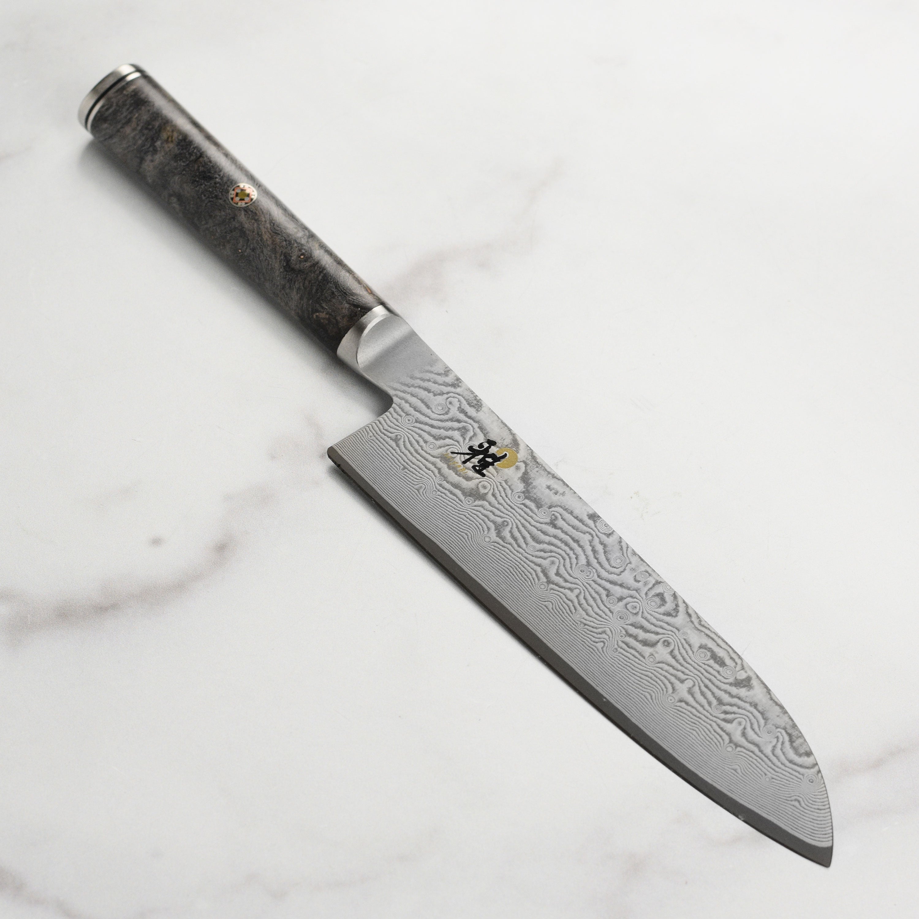 Close-up of the Miyabi Black Santoku Knife's Damascus blade and handle.