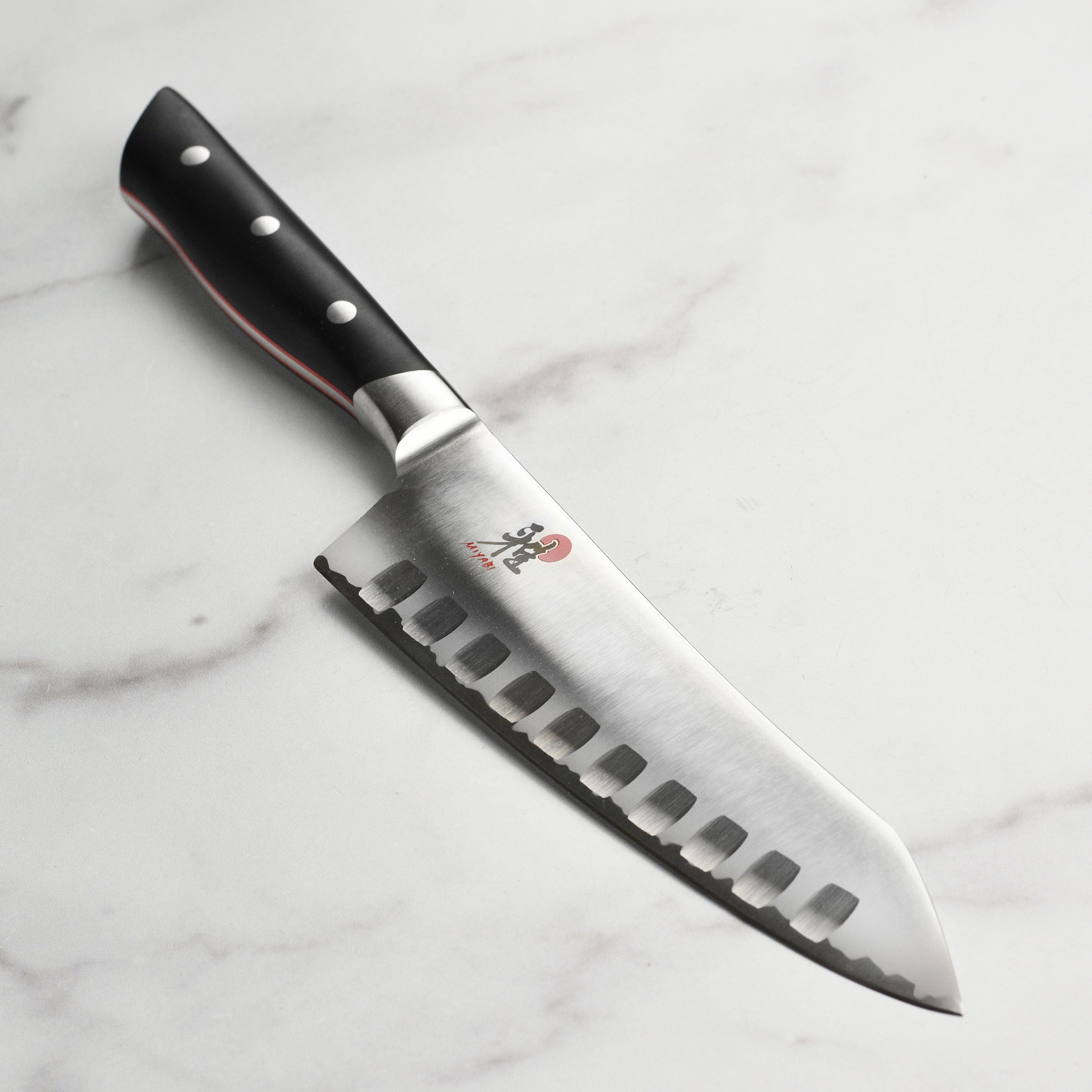 Close-up view of the Miyabi Evolution Santoku knife highlighting the sharp blade edge and hollow edge design.