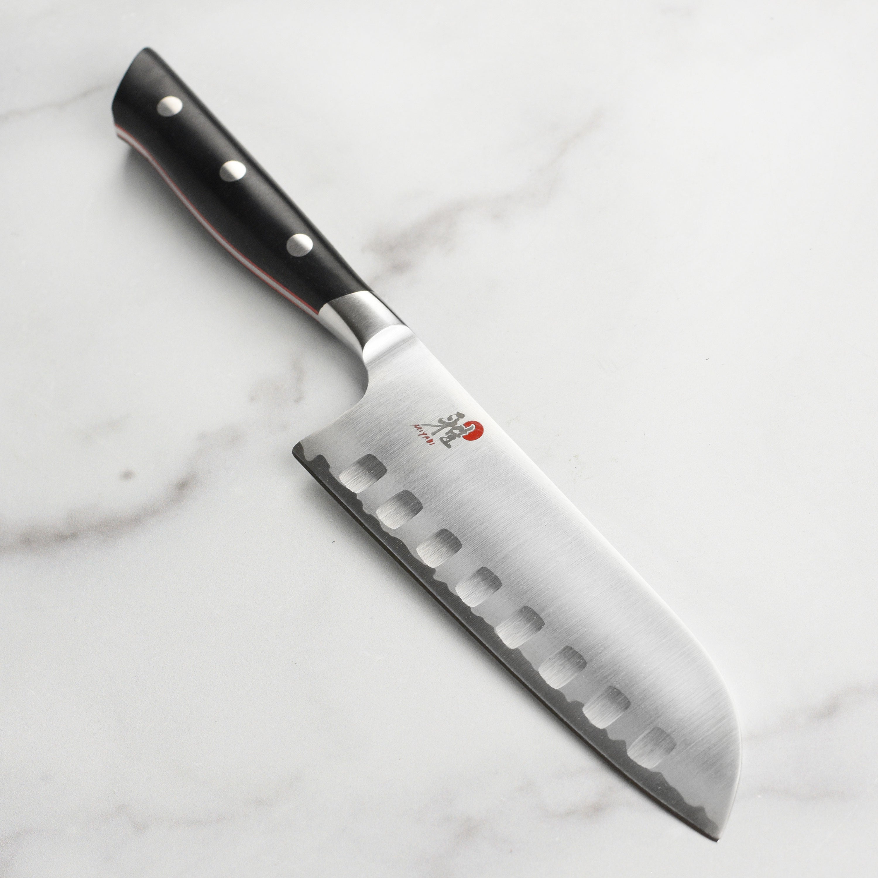 Miyabi Evolution Santoku knife showcasing the fine carbide steel blade and ergonomic handle from a side angle.