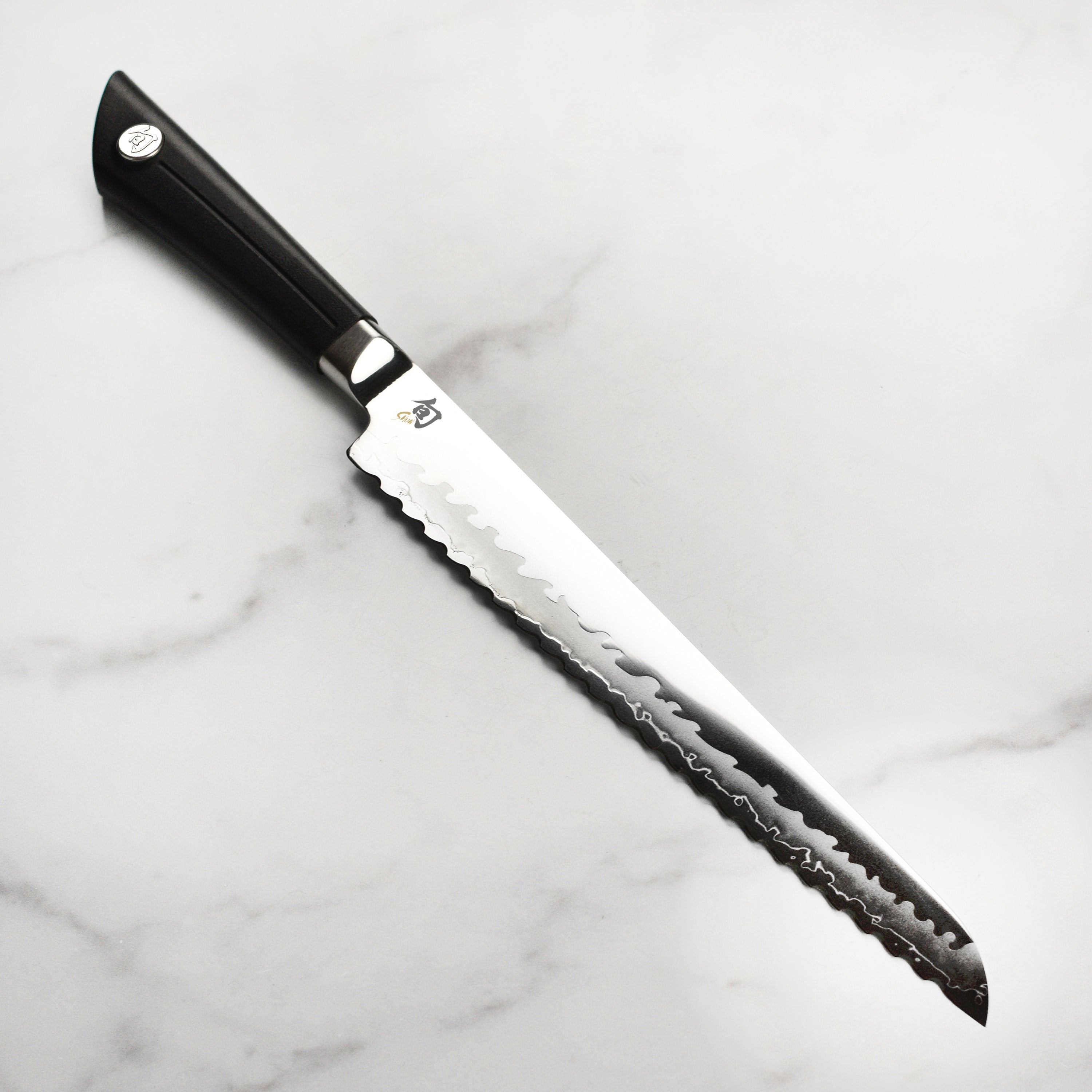 Close-up of Shun Sora 9 inch bread knife serrations and VG10 steel edge